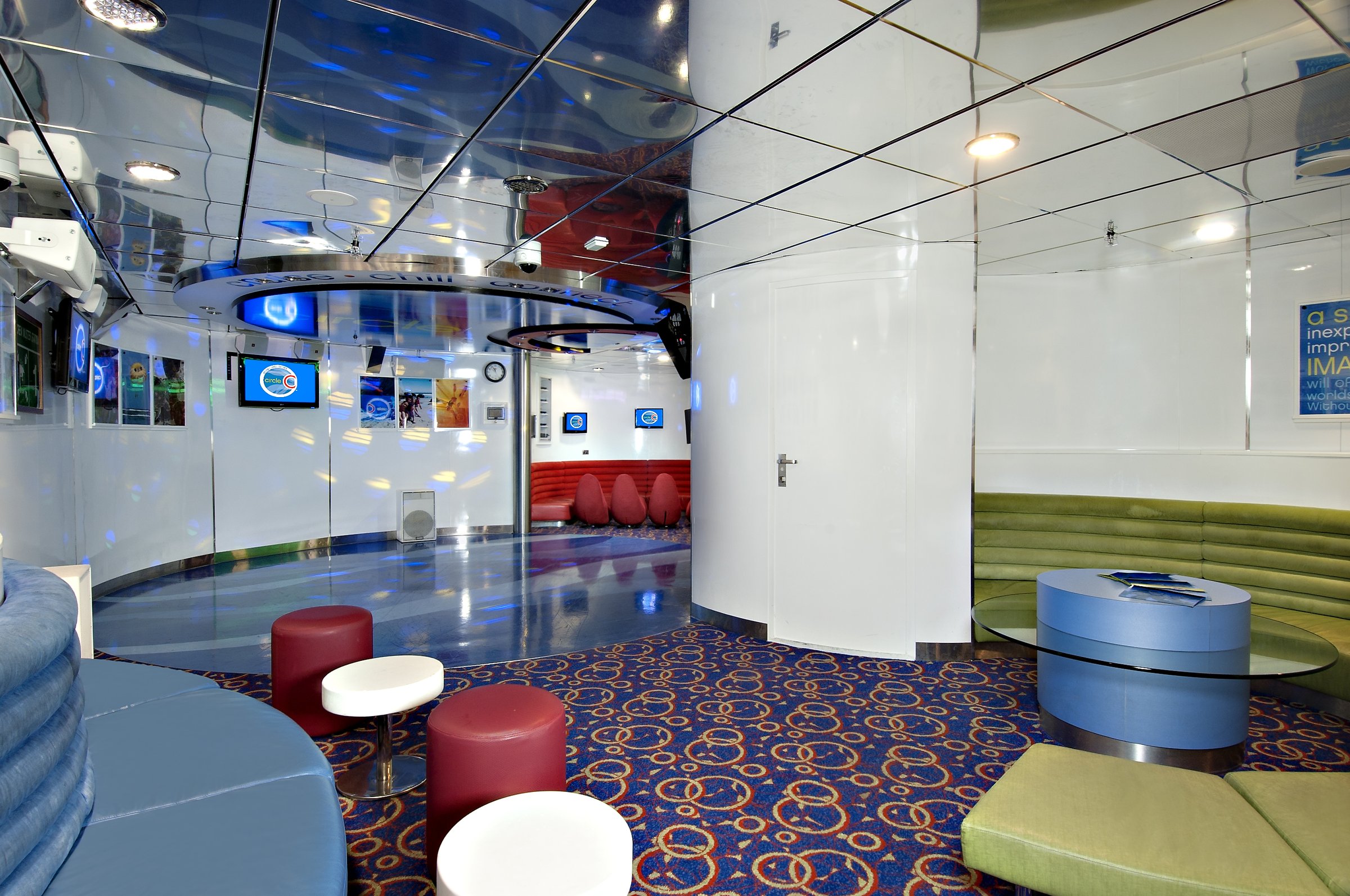 Carnival Miracle Circle C youth lounge with red poufs, green banquettes and patterned carpet