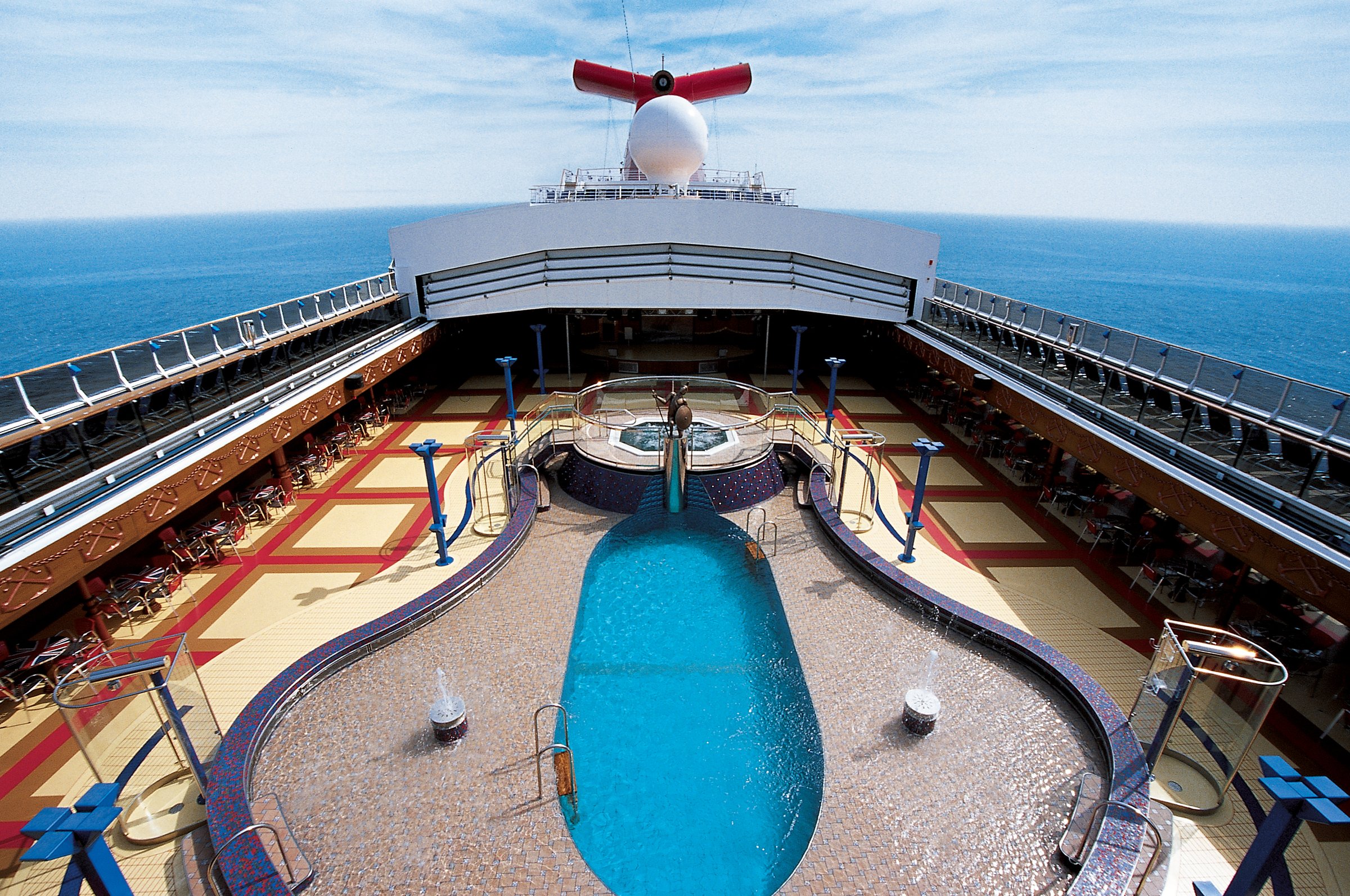 Carnival Miracle aerial-style view over the Ulysses pool deck toward the bow, funnel and open sea