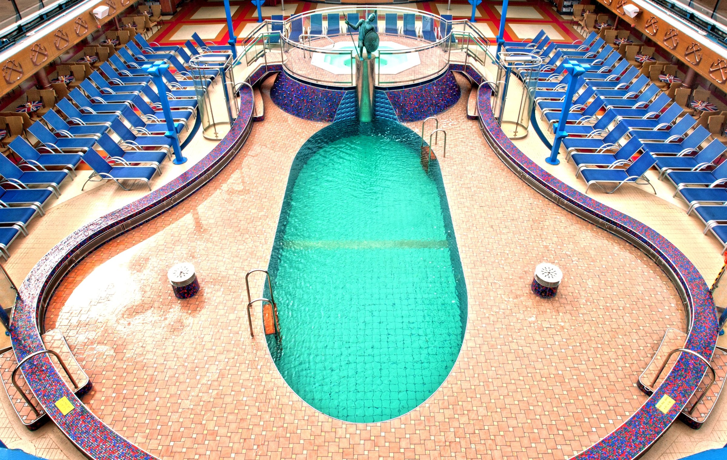 Carnival Miracle Ulysses pool from above with blue loungers around a tiled pool and fountain