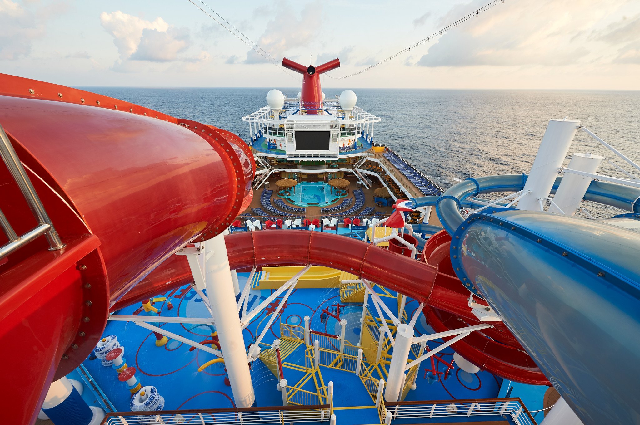 Carnival Panorama WaterWorks seen from the top of a red slide, looking forward over the splash zone to the funnel and open sea