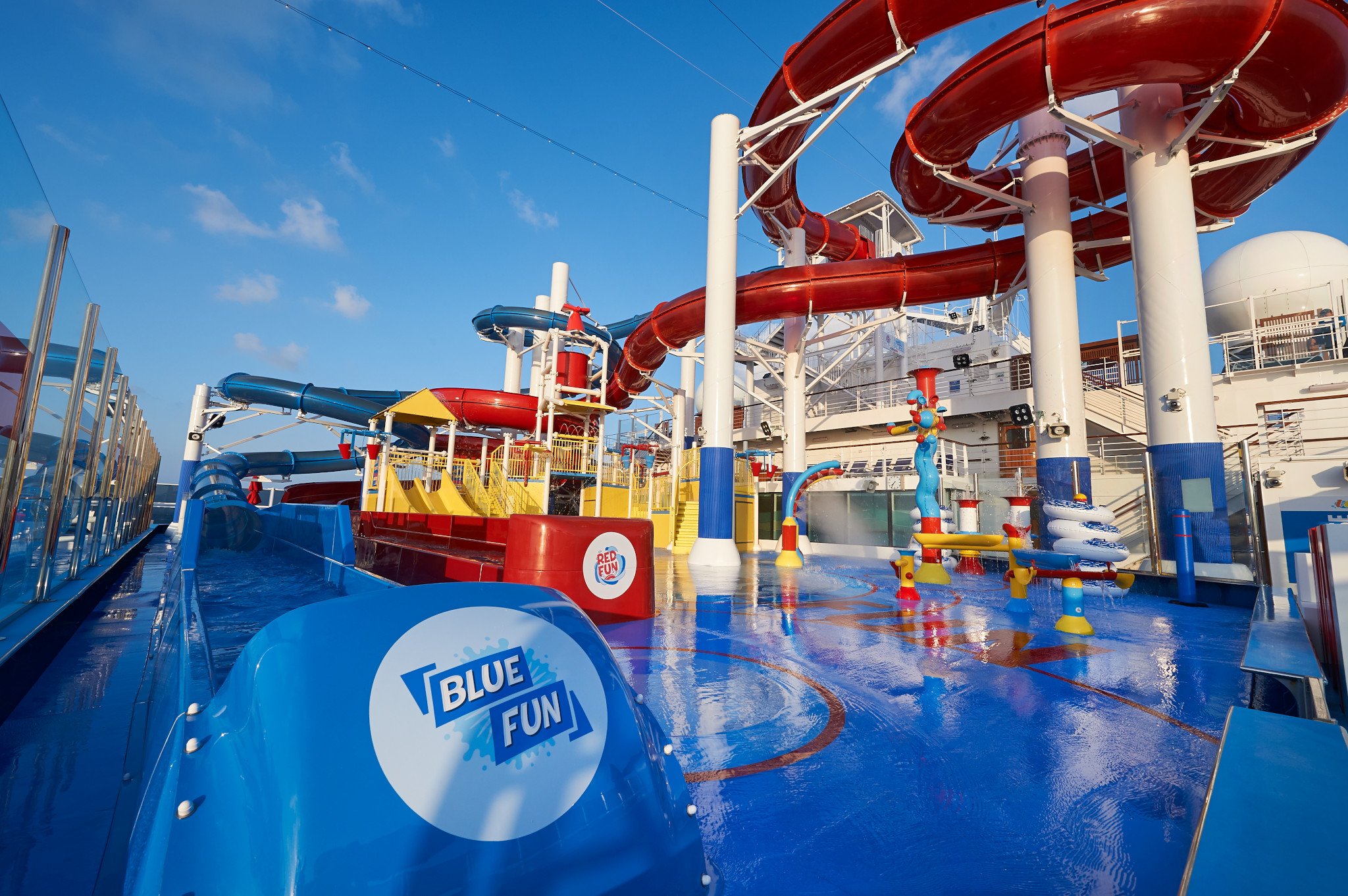 Carnival Panorama WaterWorks splash deck with blue slides, red spiral slides and water features under a blue sky