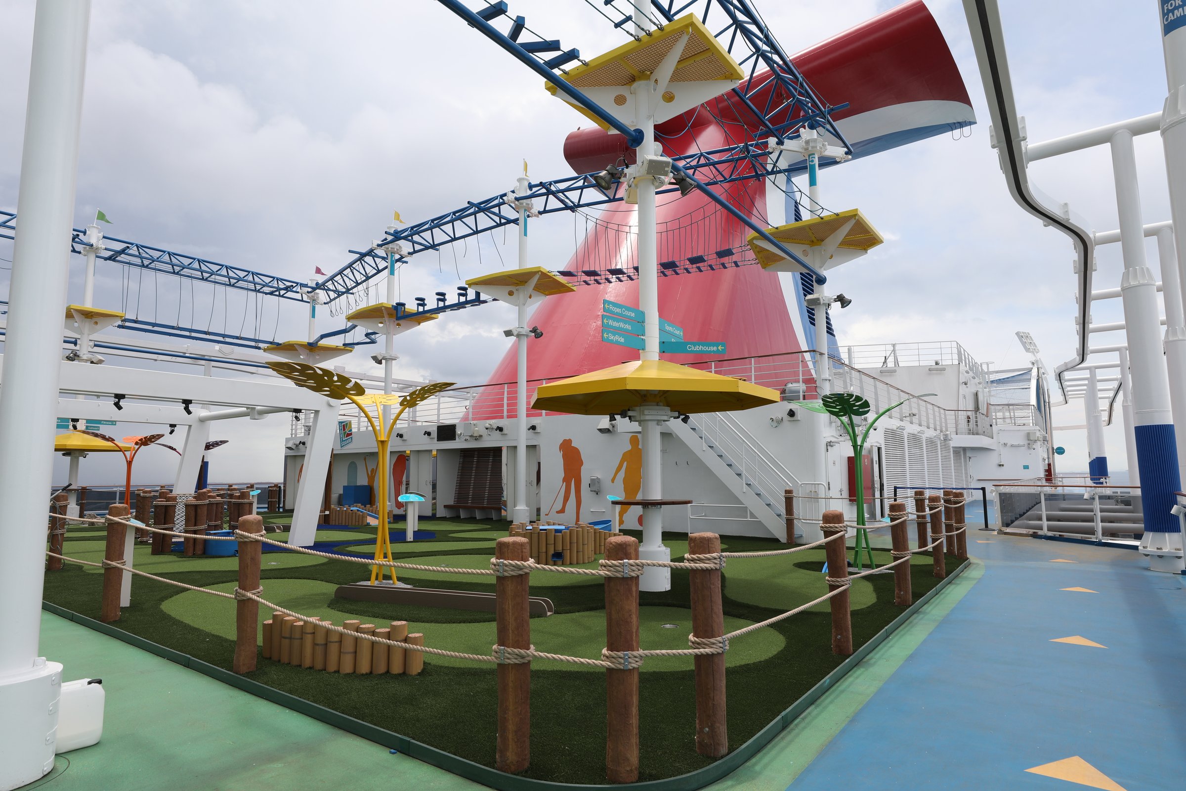 Carnival Panorama refreshed mini-golf course on the sports deck with wooden posts and yellow sun shades