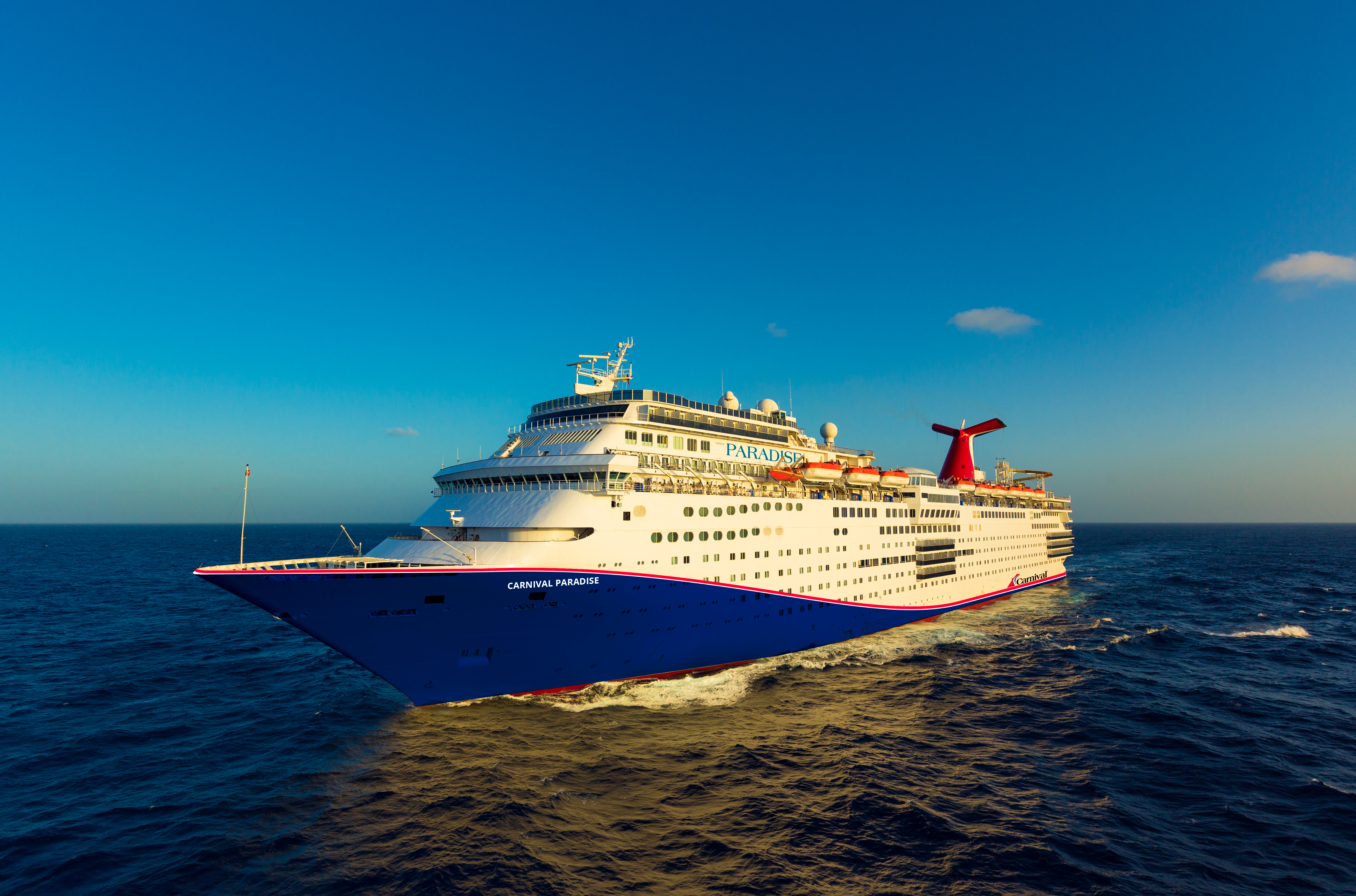 Carnival Paradise blue hull aerial at sea under clear sunny sky