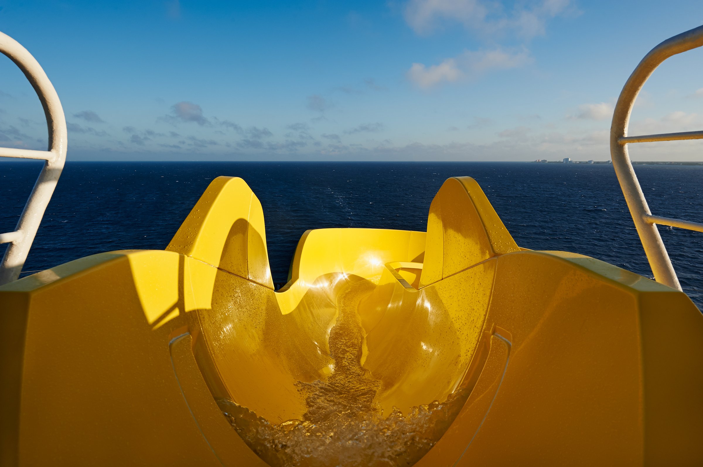 Carnival Pride WaterWorks yellow waterslide in the sun with the open ocean ahead