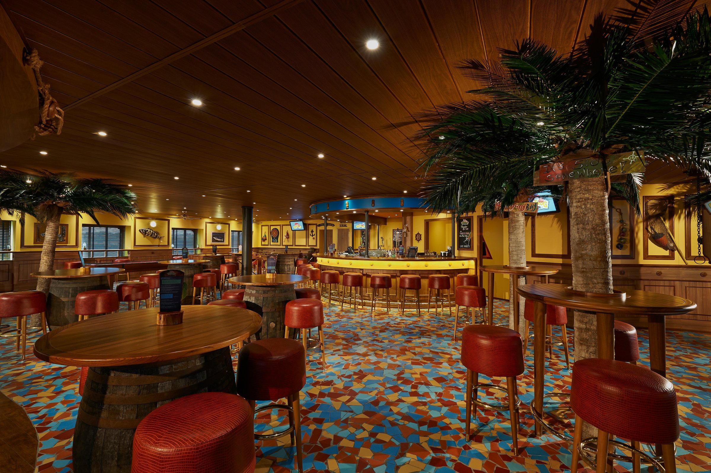 Carnival Pride Red Frog Pub with palm trees, barrel tables and red bar stools