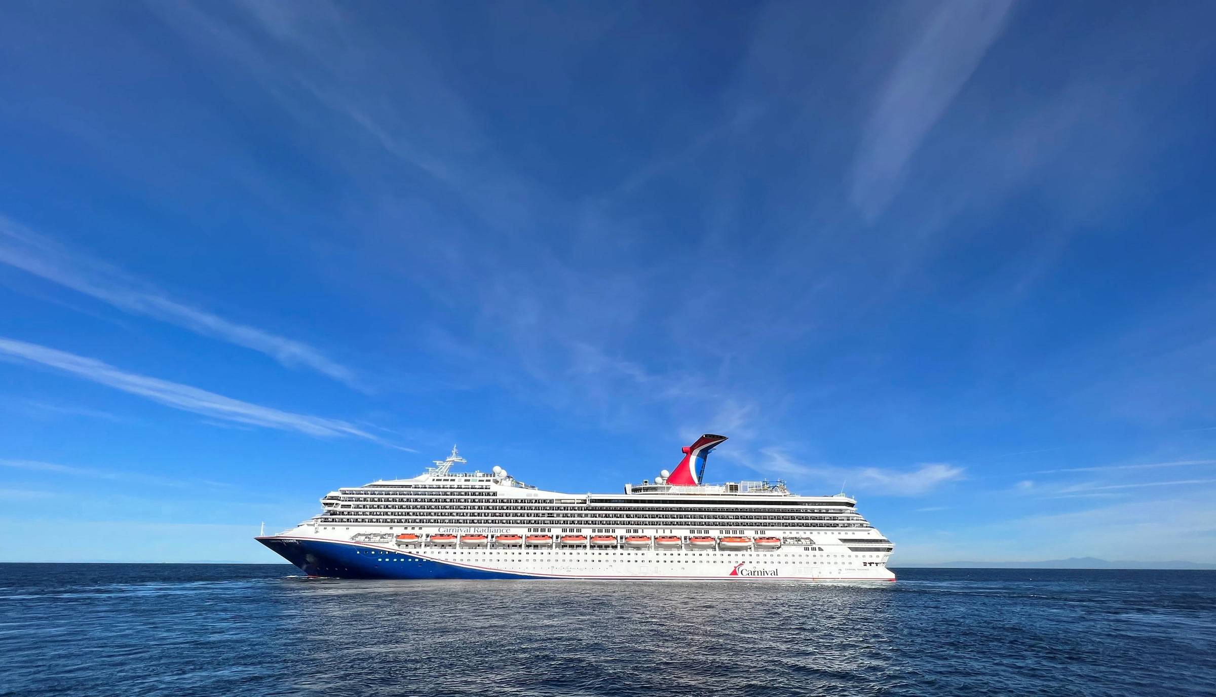Carnival Radiance blue-hull exterior at sea, sunny daylight