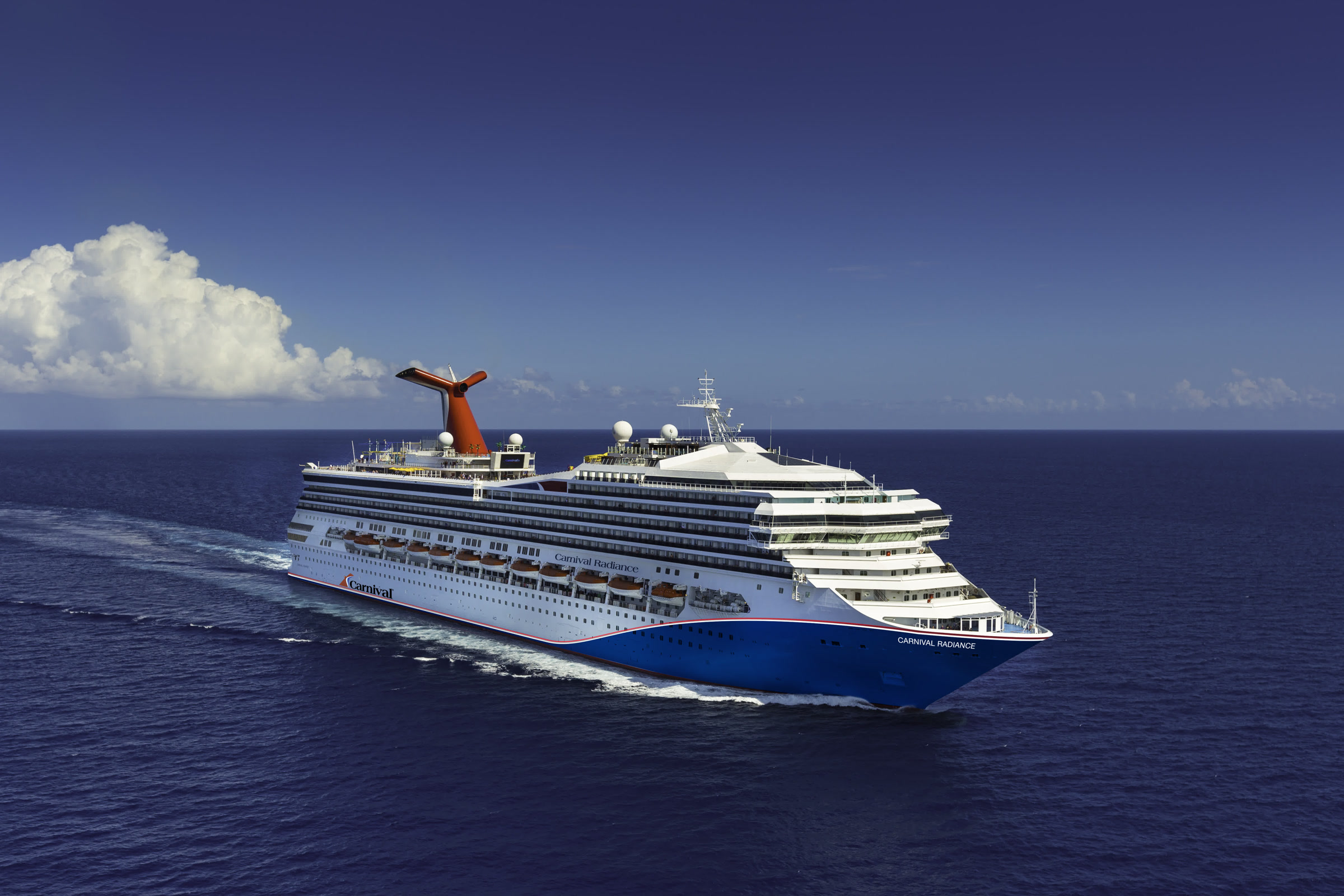 Carnival Radiance aerial blue-hull exterior in sunny open water, bright daylight