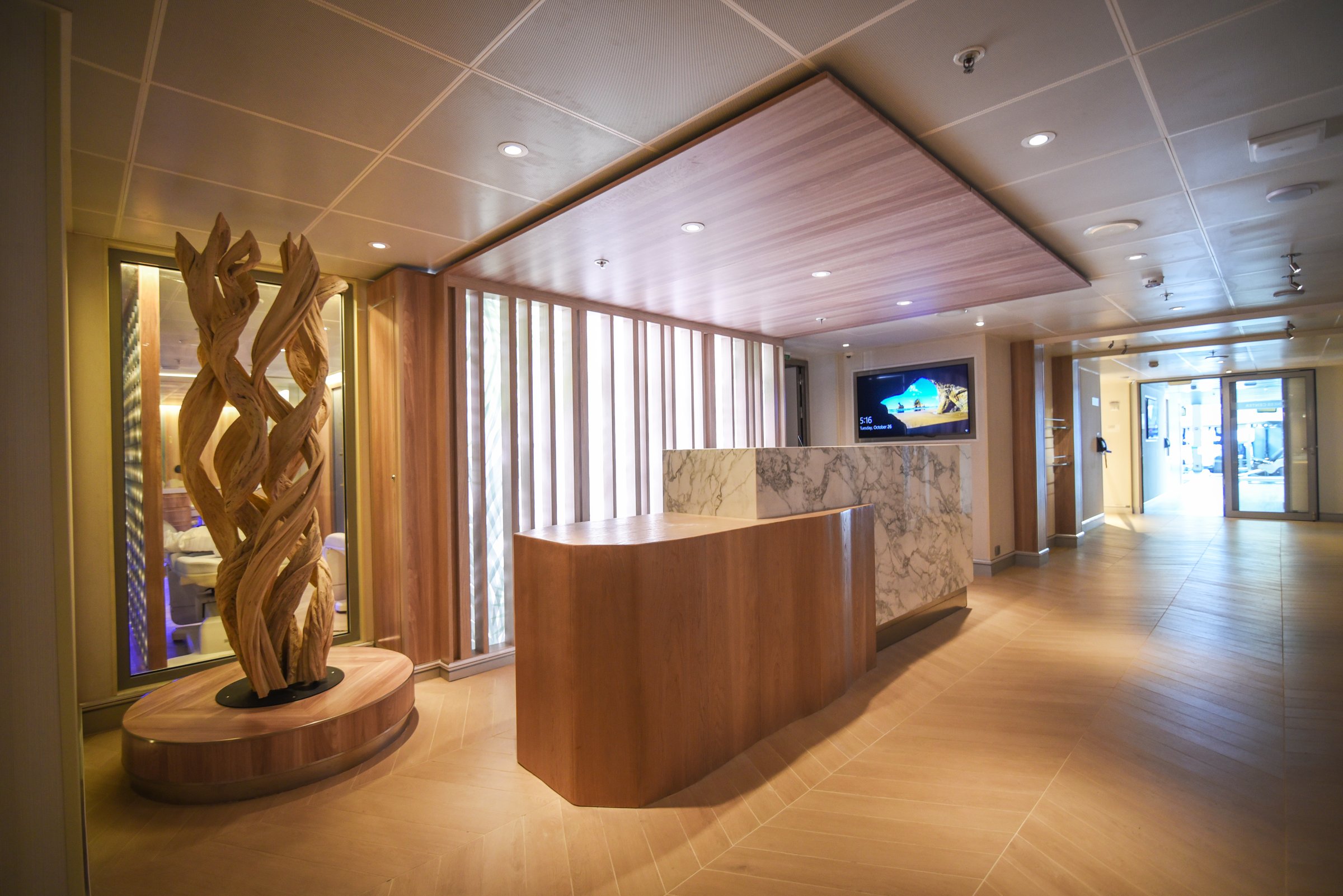 Carnival Radiance spa reception with a marble desk and a sculpted driftwood centrepiece