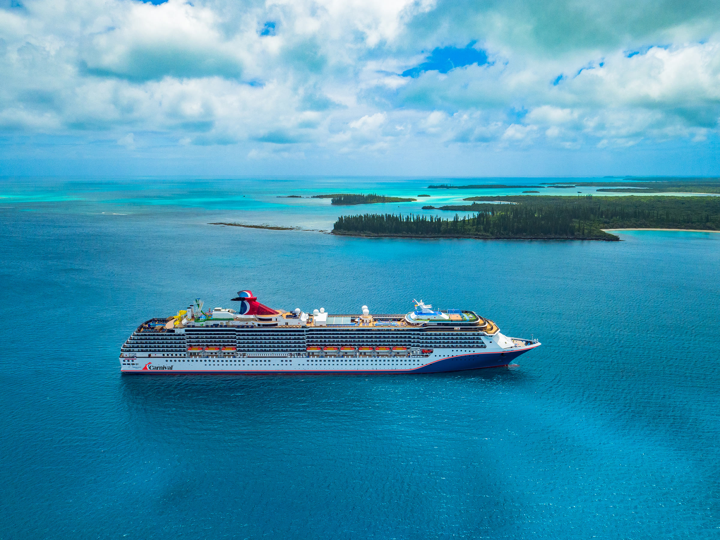 Carnival Spirit blue-hull aerial with tropical islands, sunny daylight