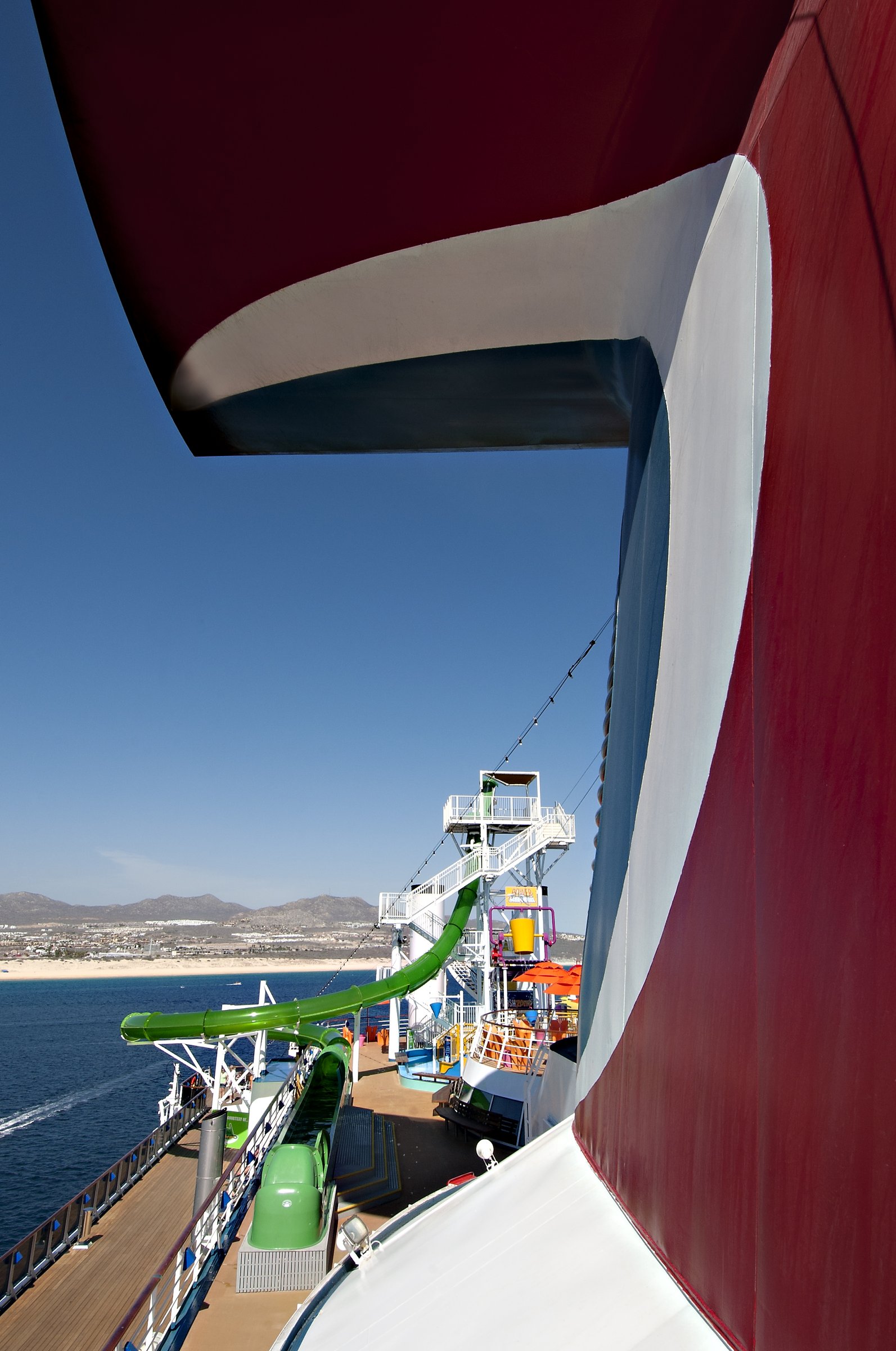 Carnival Spirit red funnel with the WaterWorks green slide and a coastline beyond