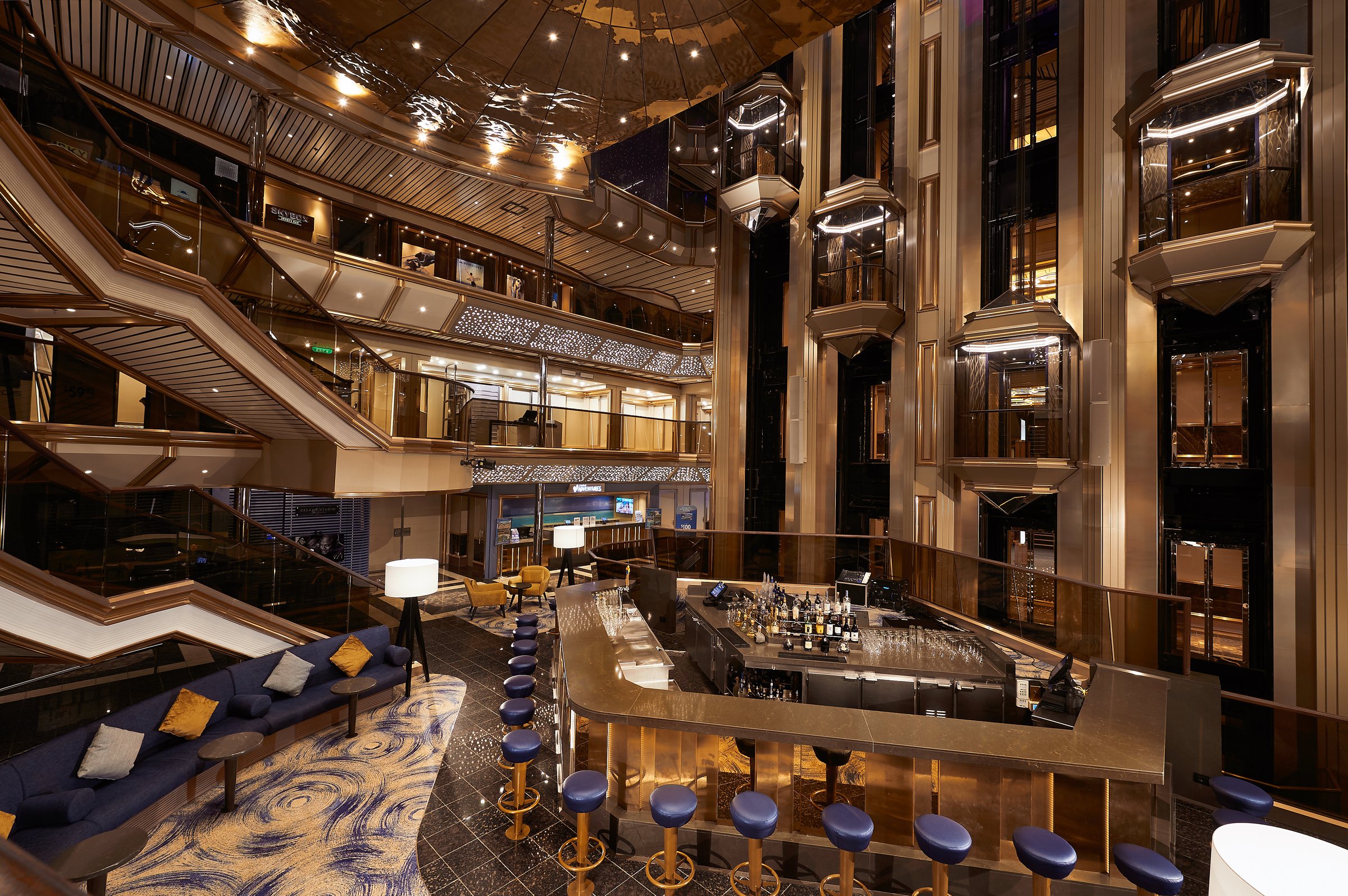 Carnival Sunrise multi-deck atrium with glass elevators, a central bar and navy seating