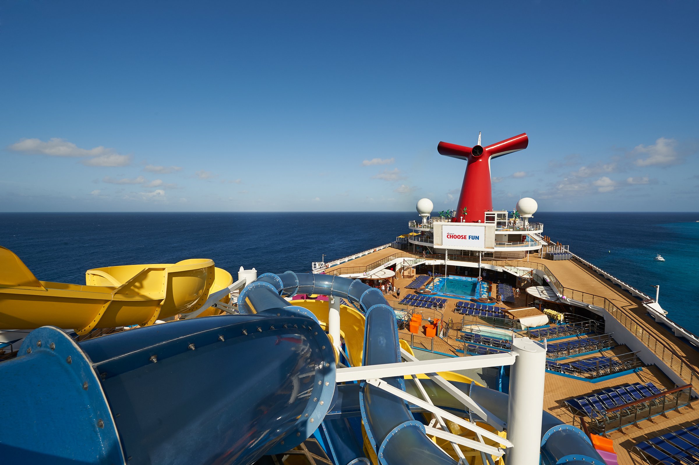 Carnival Sunrise WaterWorks slides with the funnel and pool deck in the distance under a deep blue sky