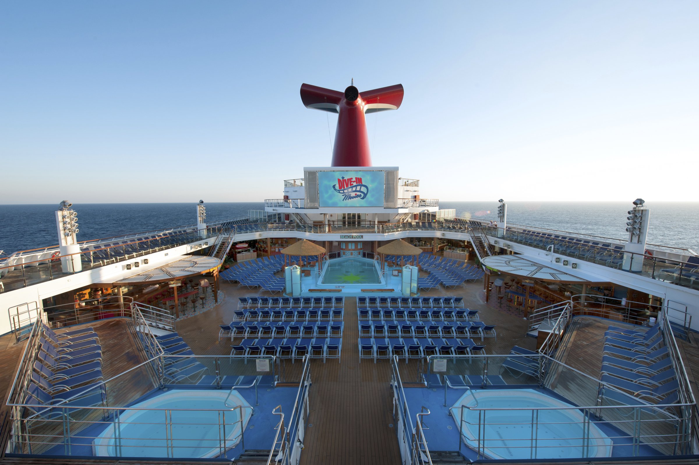 Carnival Sunshine pool deck with blue loungers and the pool in bright daylight