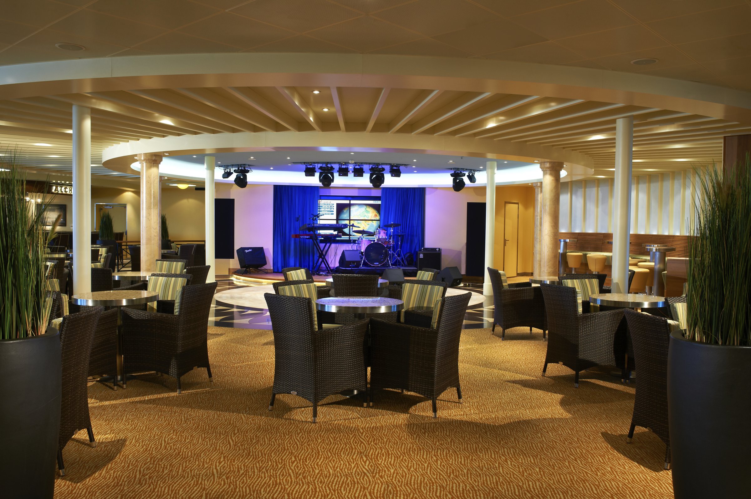Carnival Sunshine Ocean Plaza lounge with wicker seating around a small stage