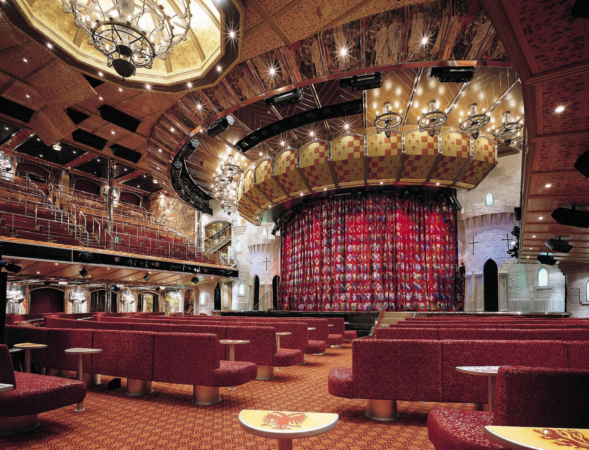 Carnival Valor main show lounge with red banquette seating and a patterned stage curtain
