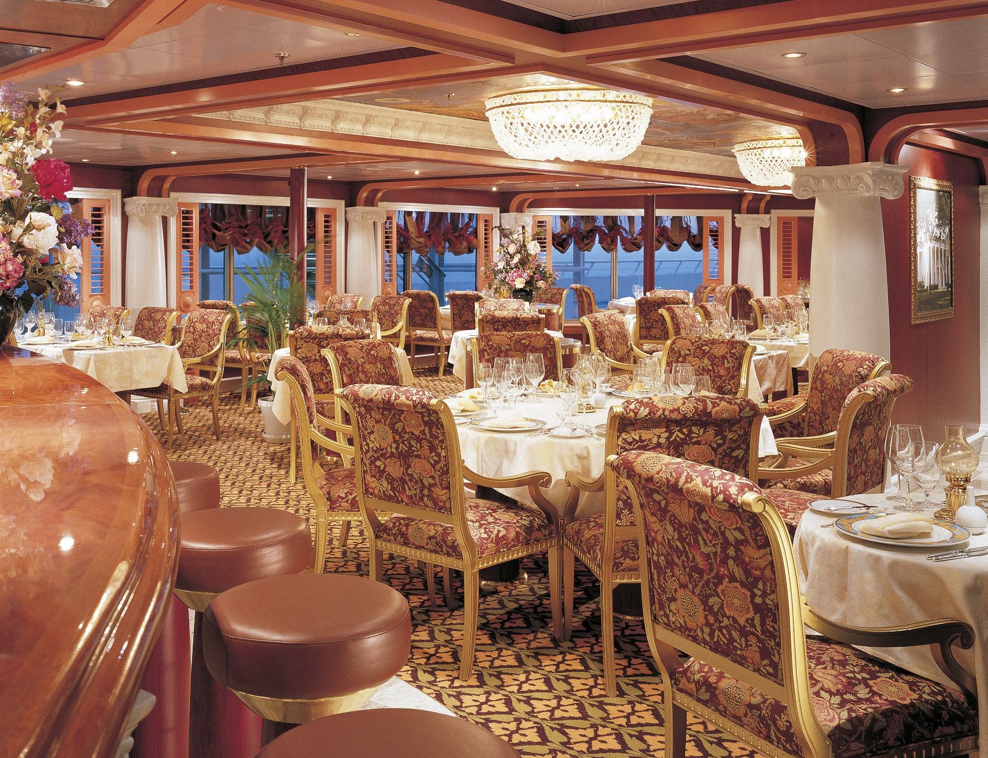 Carnival Valor formal dining room with floral chairs, white linens and crystal chandeliers