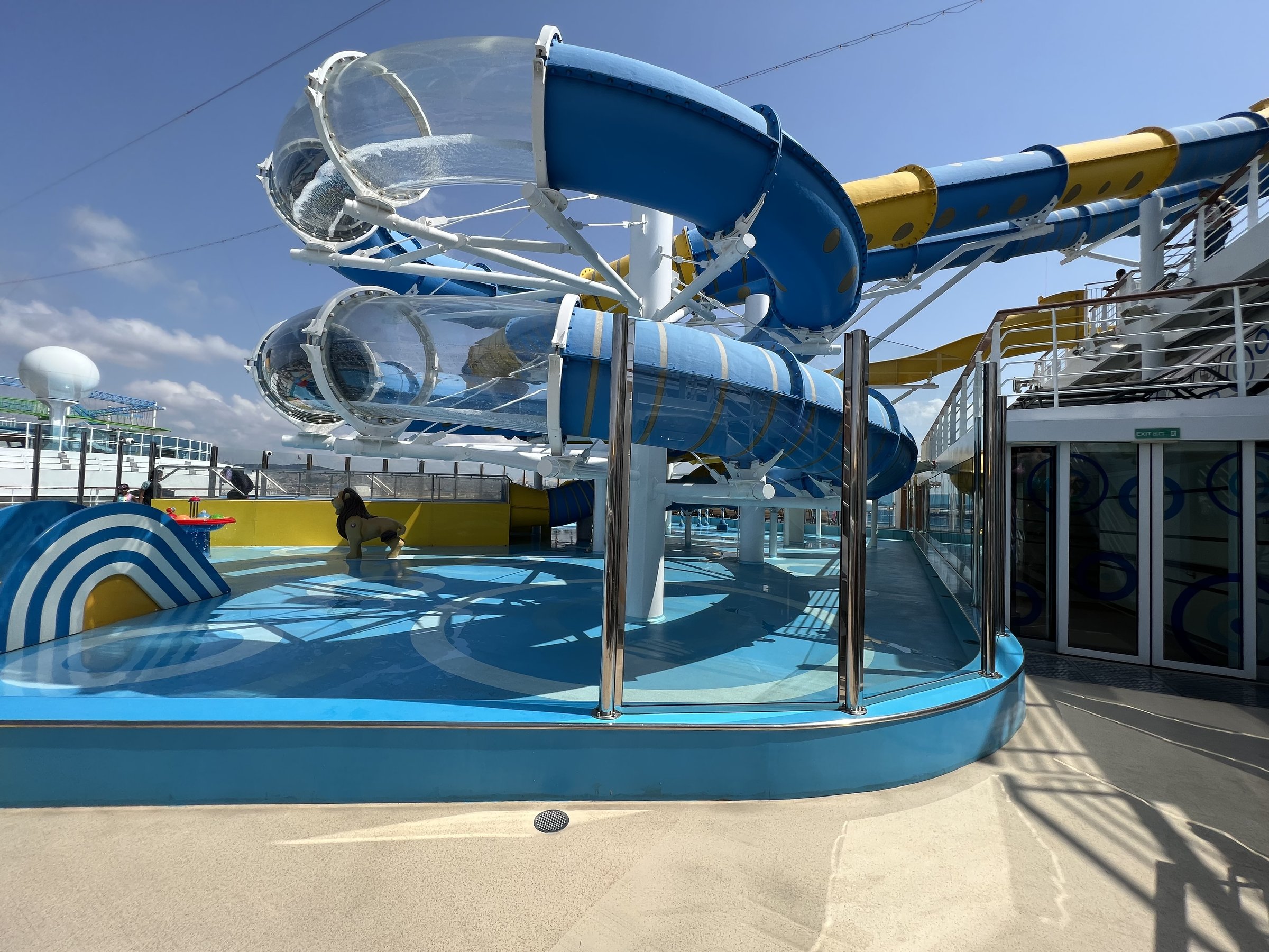Carnival Venezia WaterWorks with clear and blue tube slides above the splash deck on a sunny day