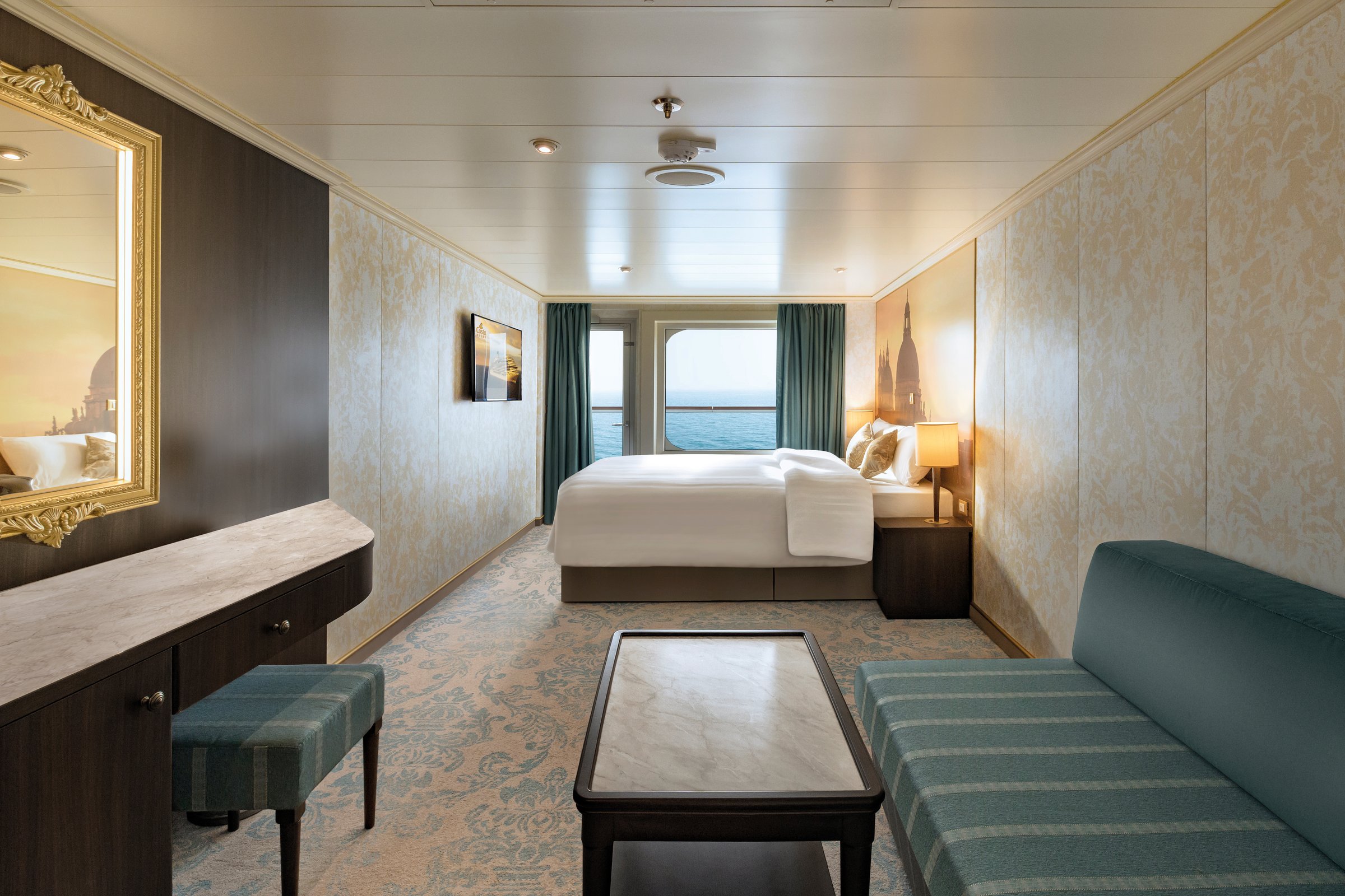 Carnival Venezia balcony stateroom with a double bed, sofa and Venice-themed decor