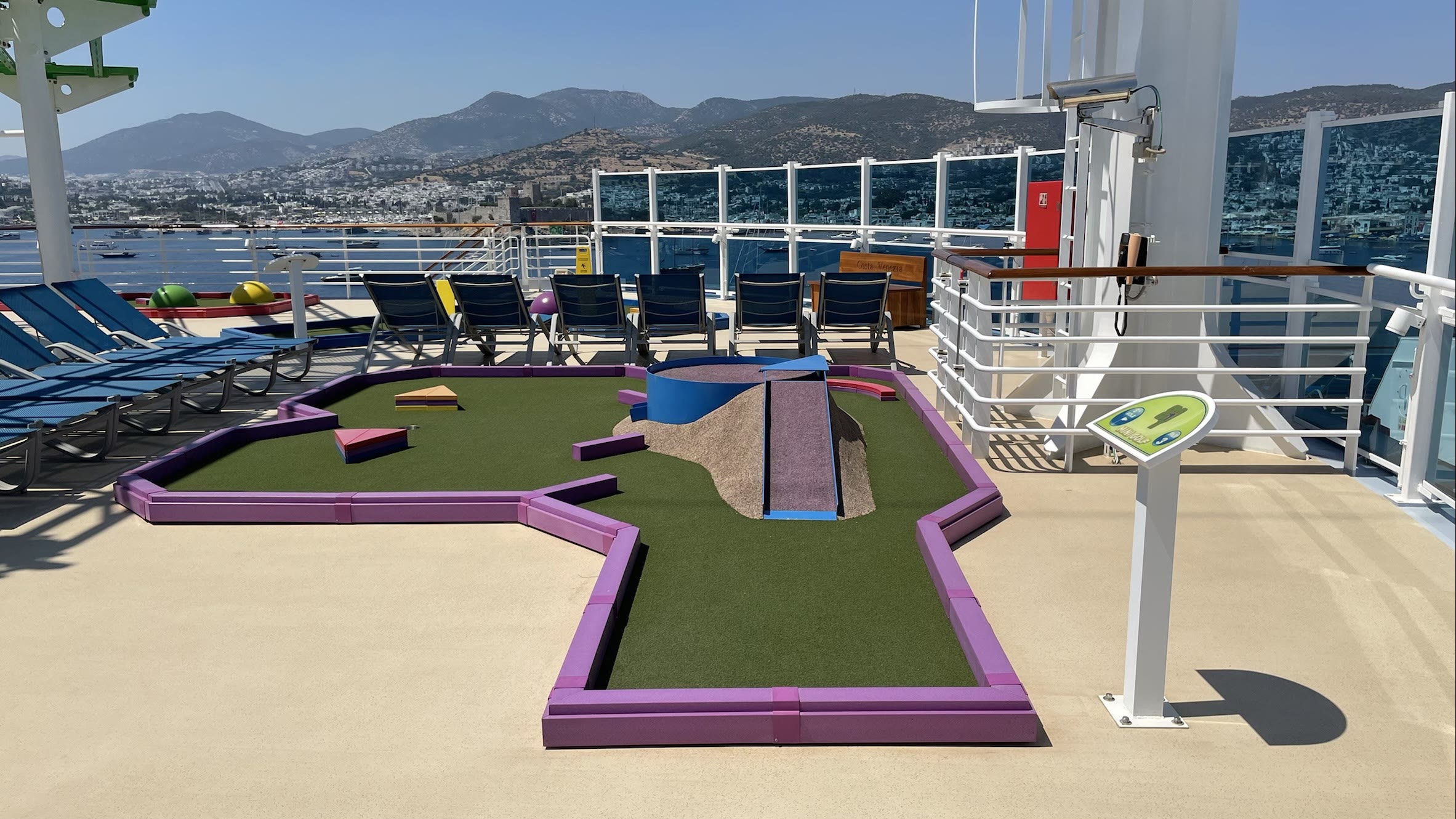 Sunny mini golf deck with coastal port view aboard Carnival Venezia