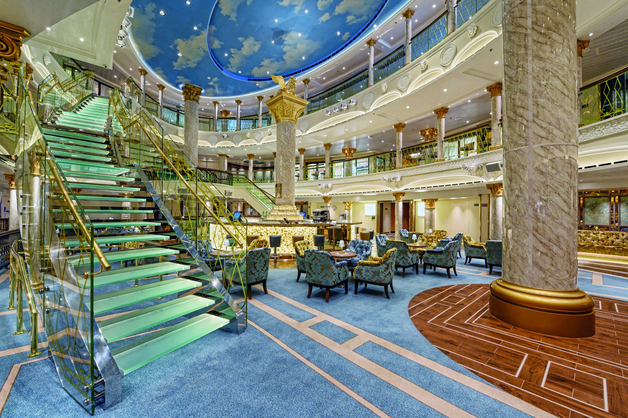 Carnival Venezia multi-deck atrium with a glass staircase, marble columns and painted sky ceiling