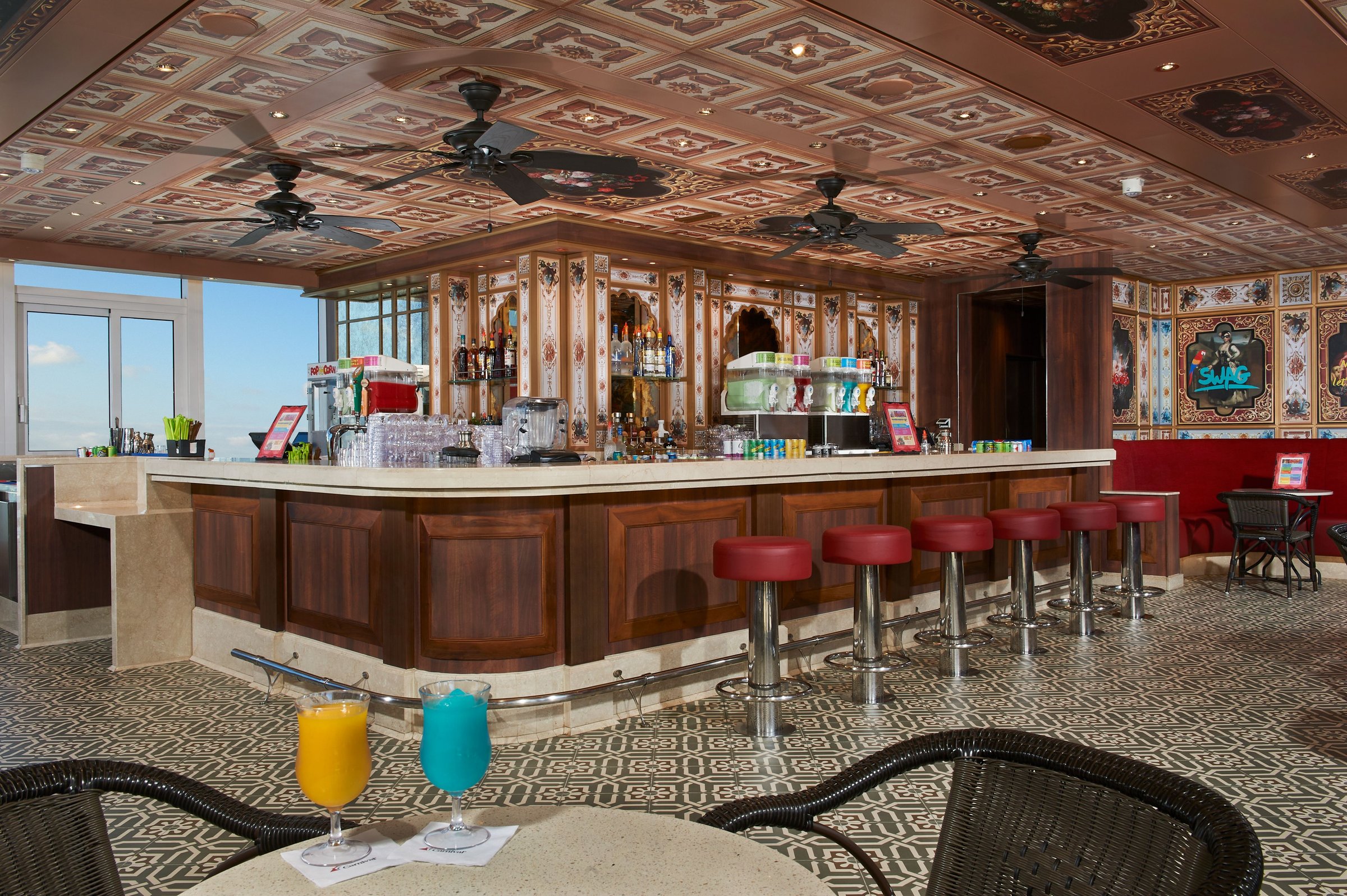 Carnival Venezia Rococo Bar with red stools, a carved wood bar front and ornate coffered ceiling