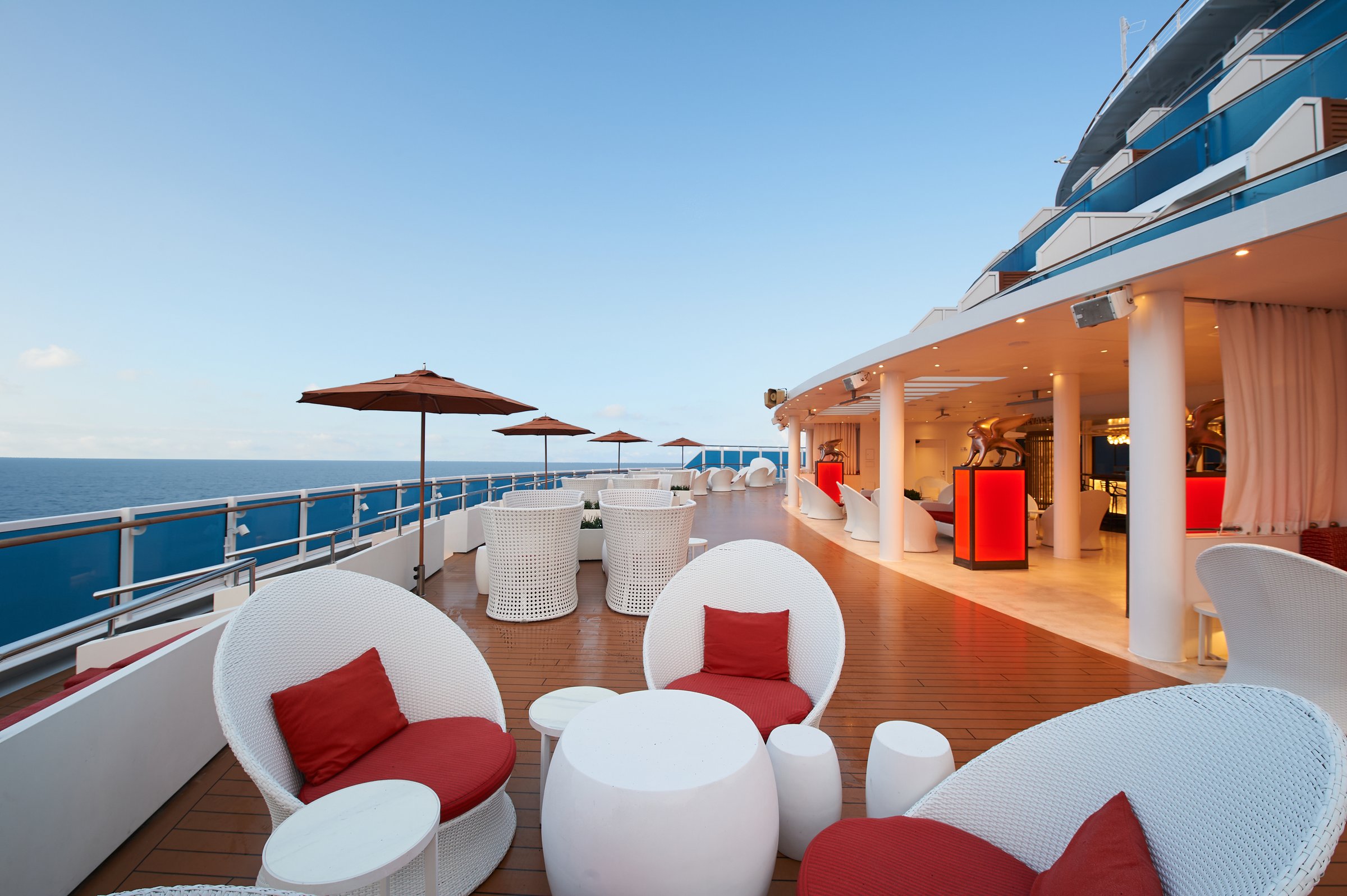 Carnival Venezia Carnevale Bar outdoor terrace with white wicker chairs and red cushions by the sea rail