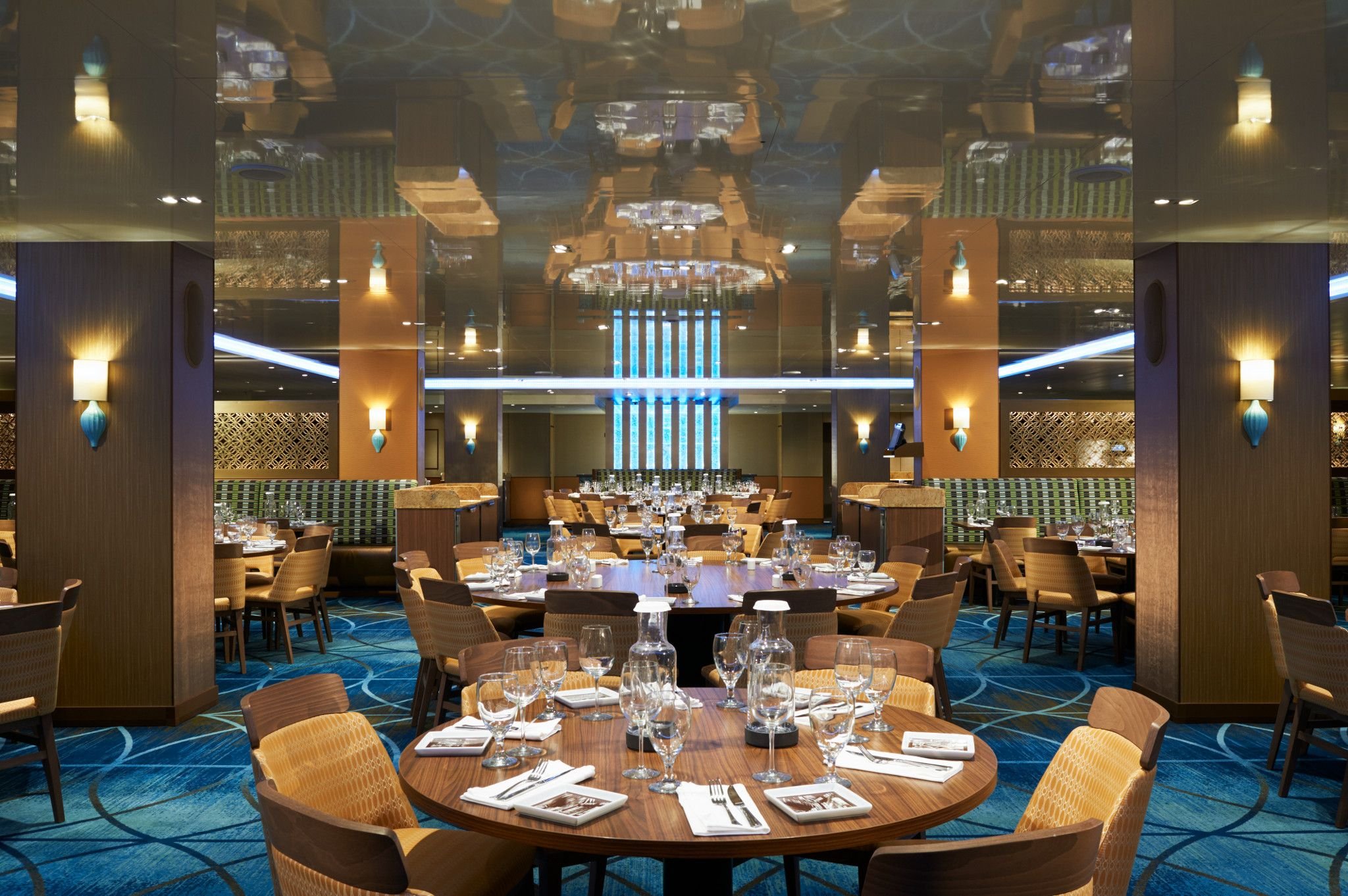 Carnival Vista Reflections dining room with set round tables, blue patterned carpet and mirrored ceiling