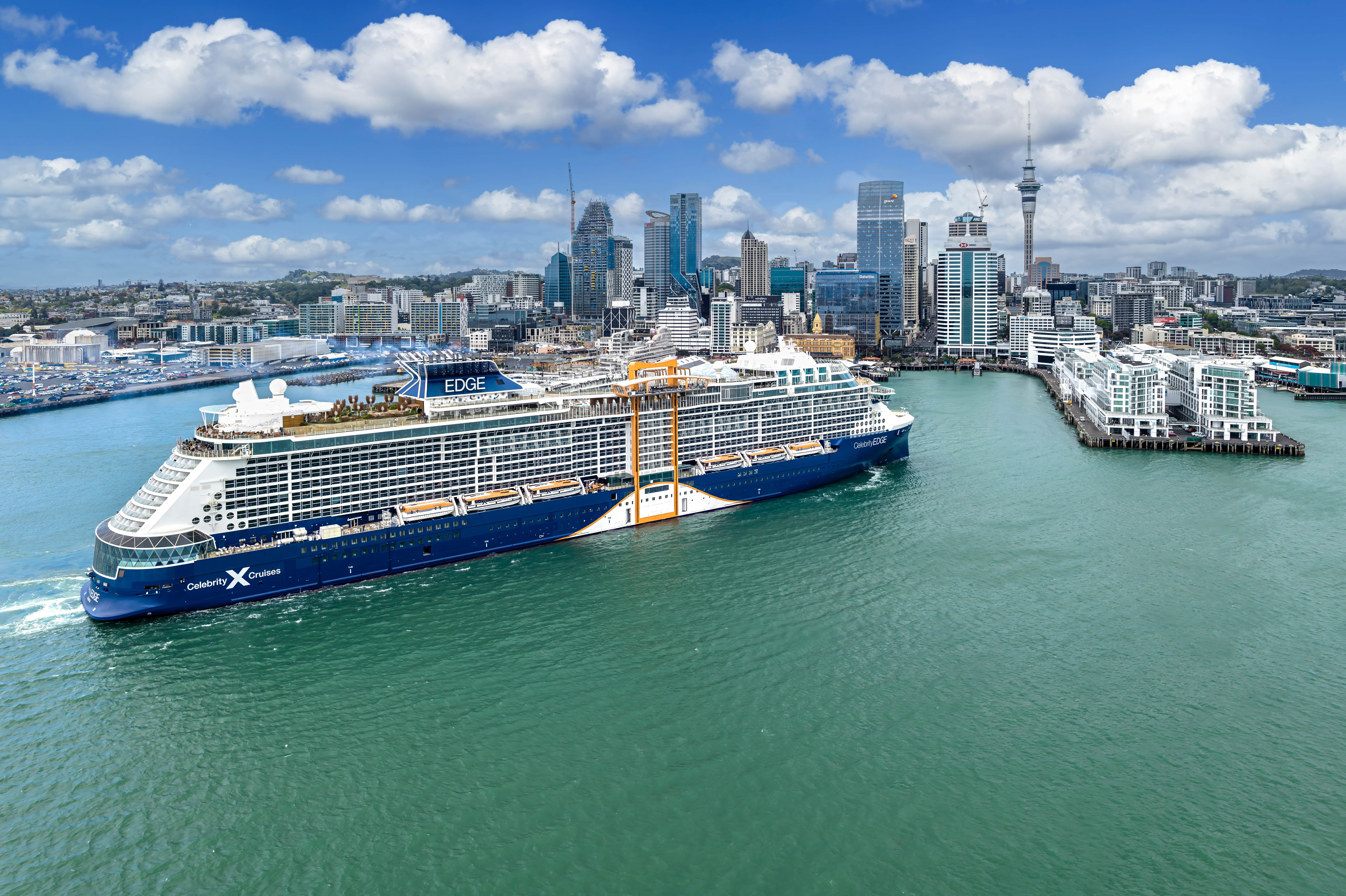 Celebrity Edge aerial exterior sailing into sunny Auckland harbour