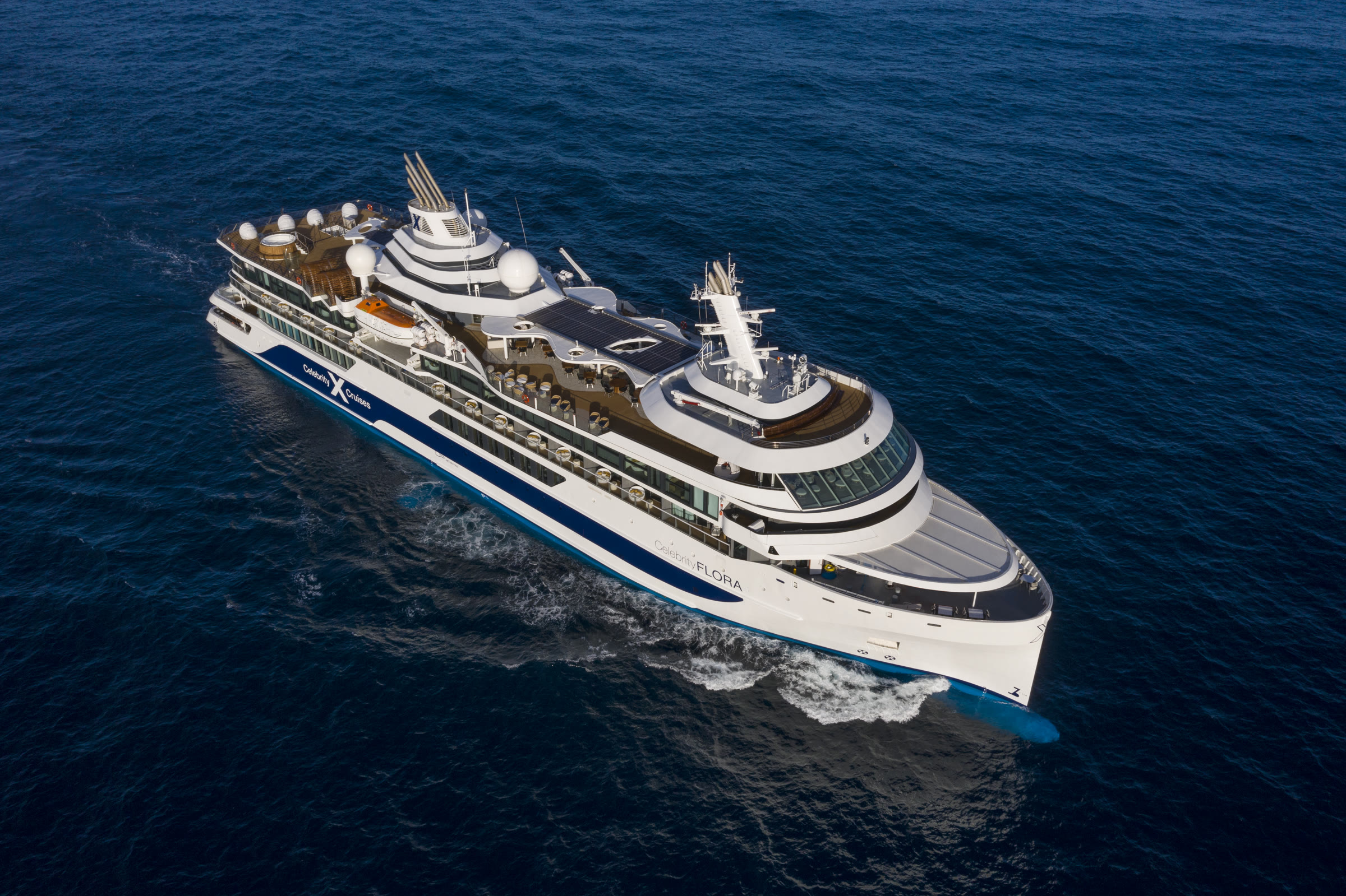 Celebrity Flora sunny aerial view of the whole ship over deep blue ocean