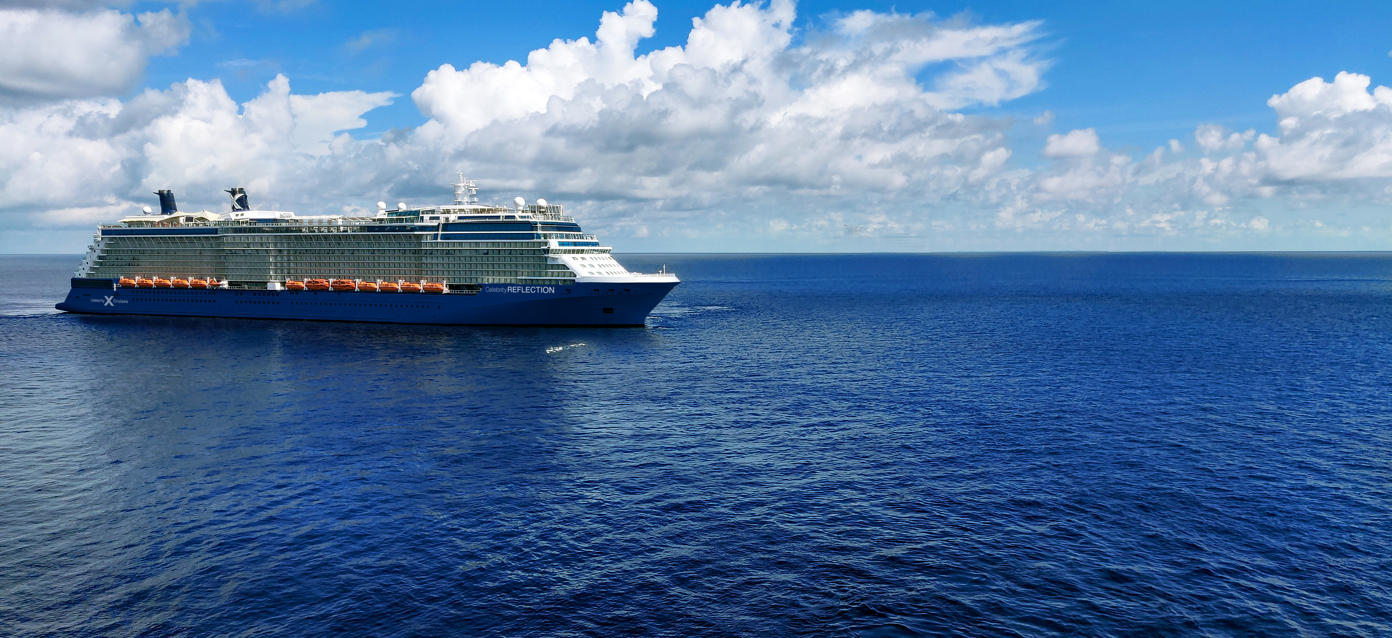 Celebrity Reflection sunny aerial exterior sailing under a blue sky