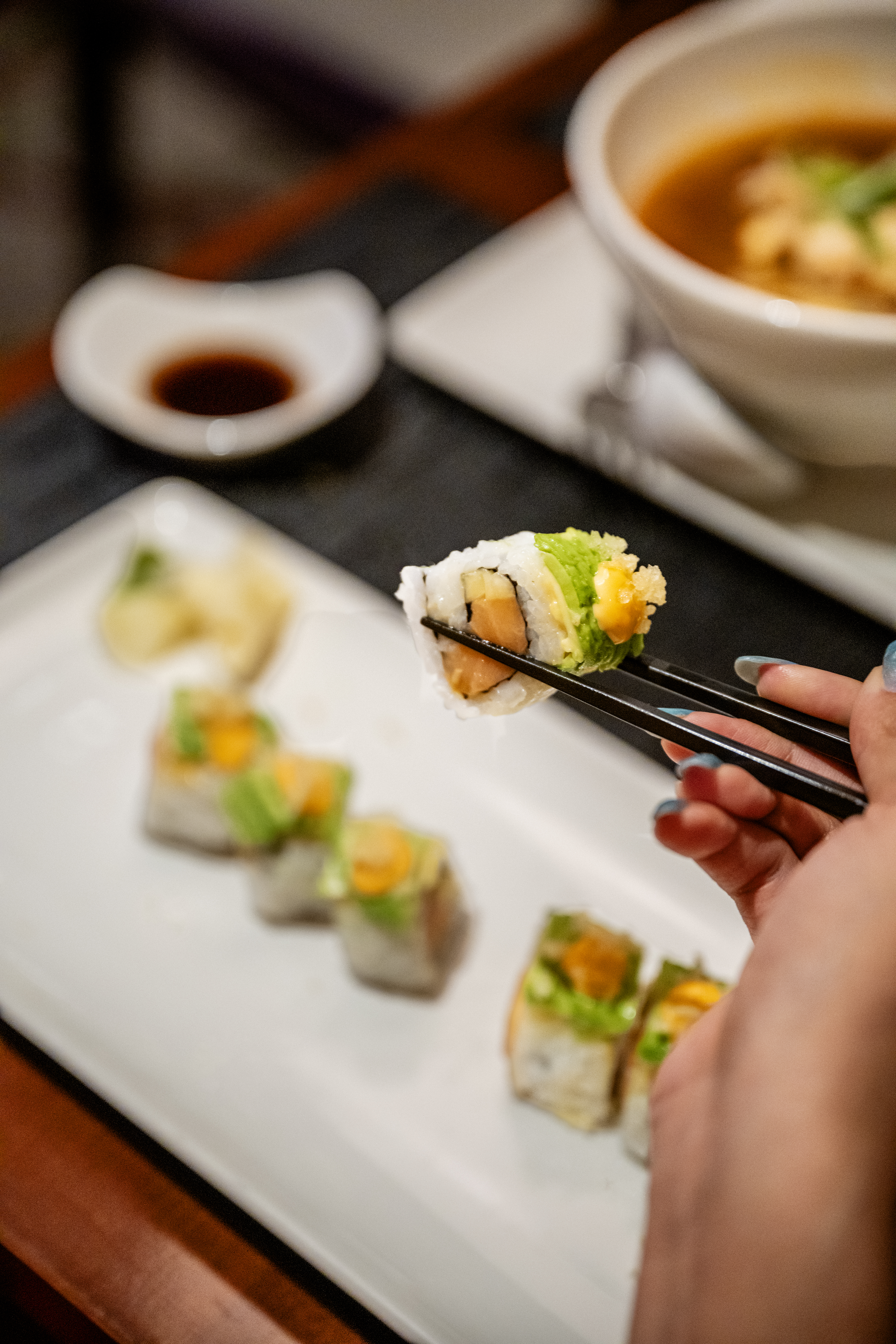Celebrity Summit Sushi on Five roll lifted with chopsticks
