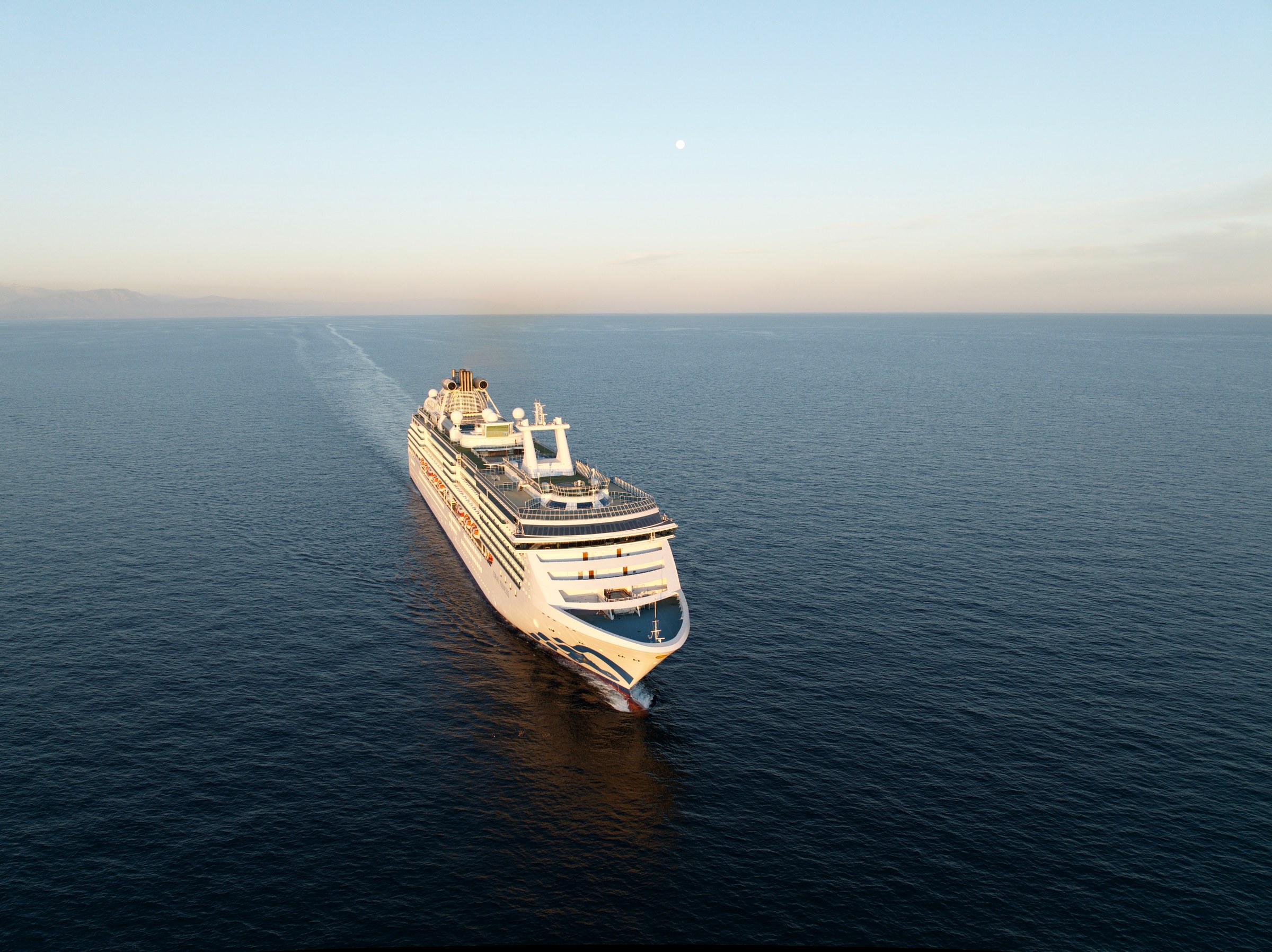 Aerial rear three-quarter of Coral Princess at sea in warm light