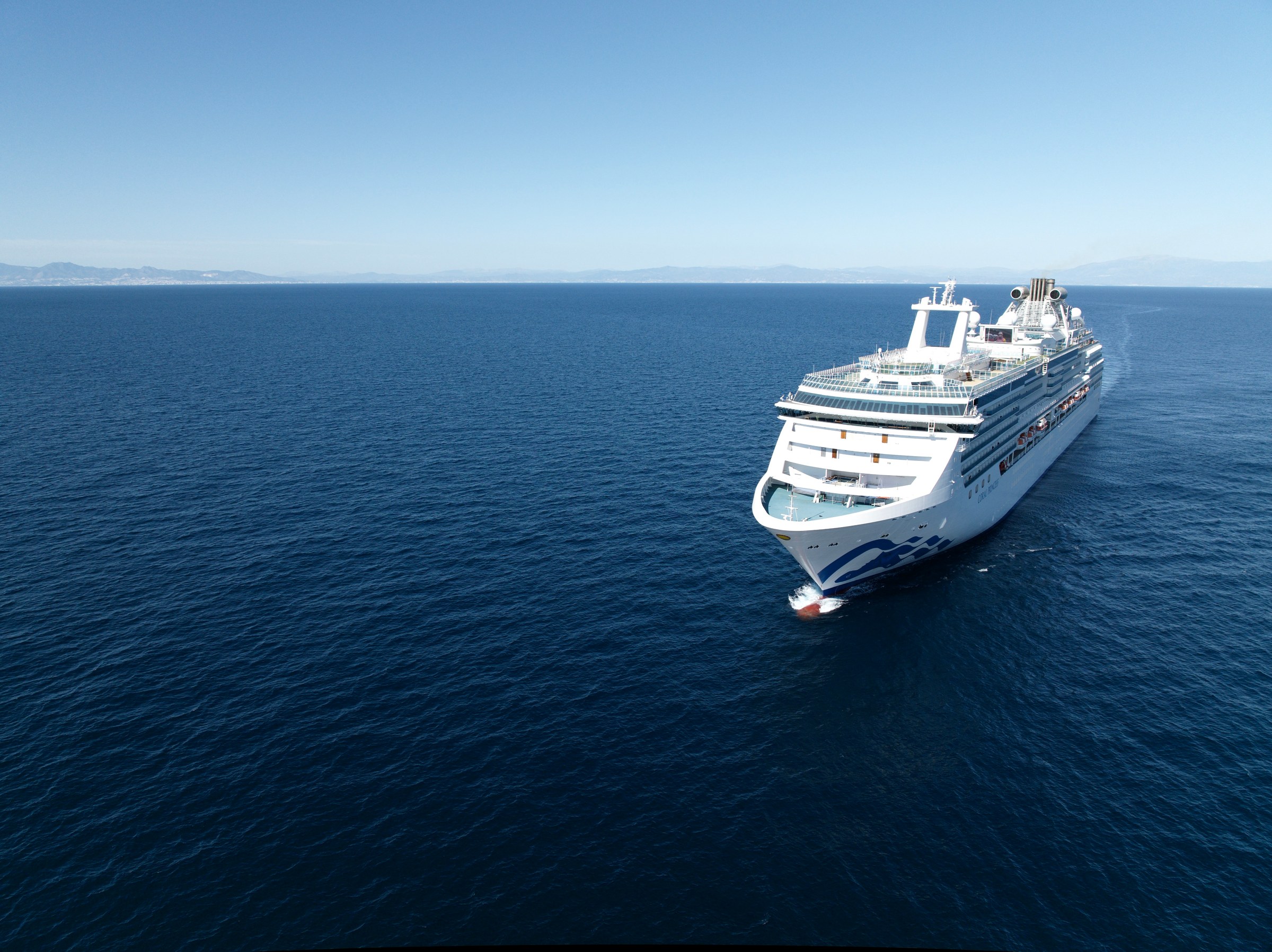 High aerial of Coral Princess heading across open blue water
