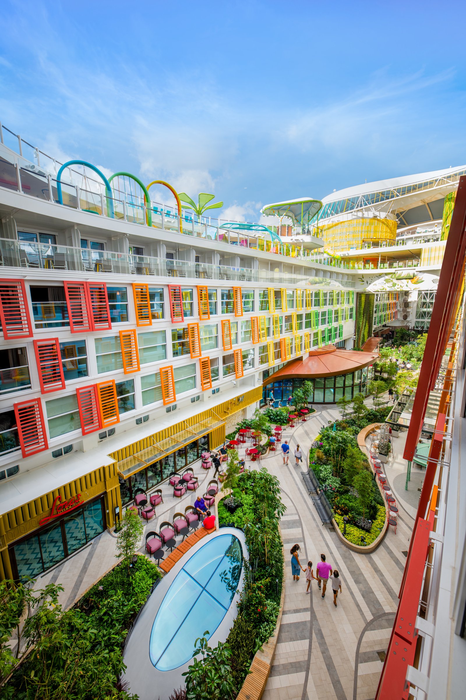 Central Park aboard Icon of the Seas, with gardens and cafe tables under a blue sky