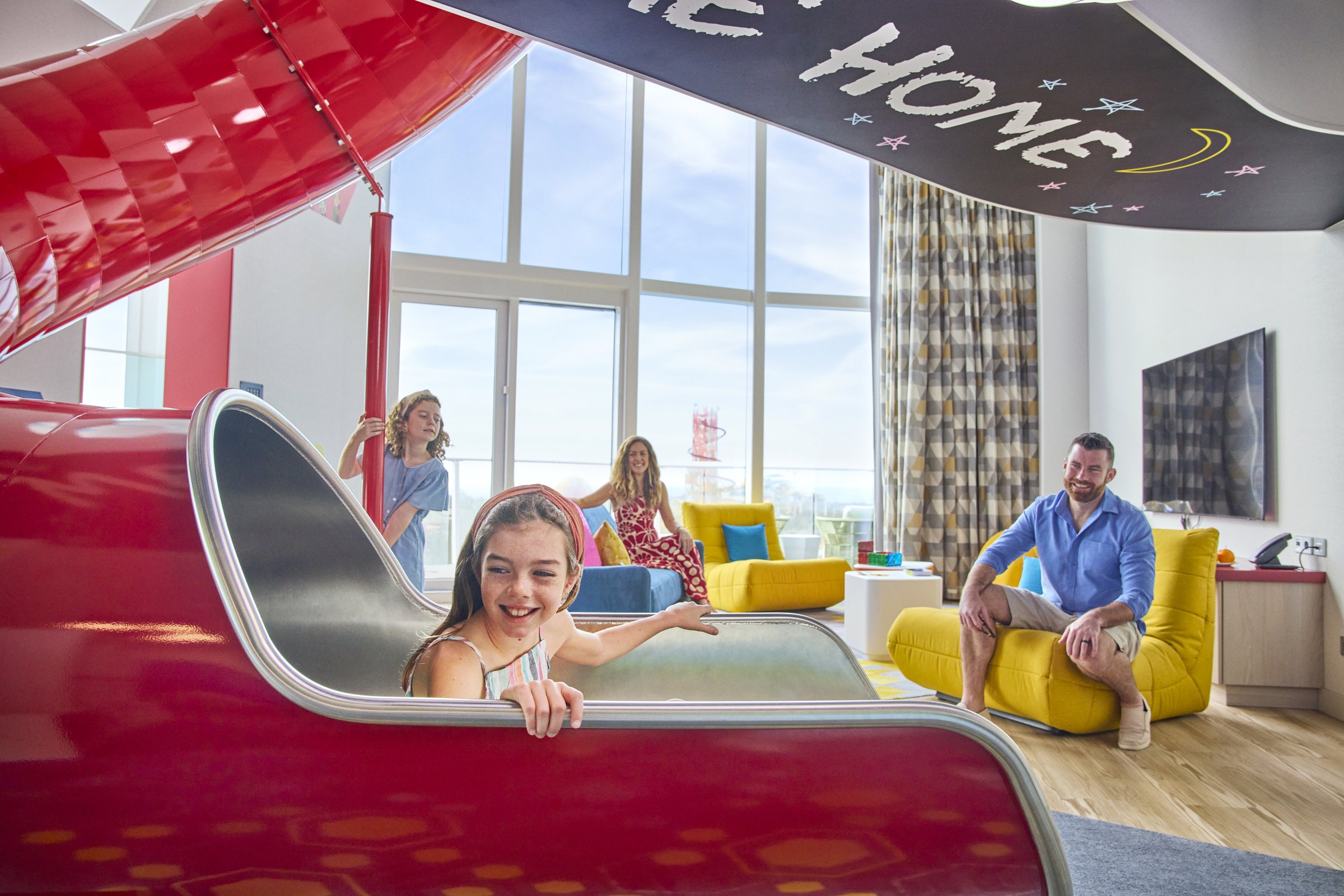 Family relaxing in the Ultimate Family Townhouse with its in-suite red slide aboard Icon of the Seas