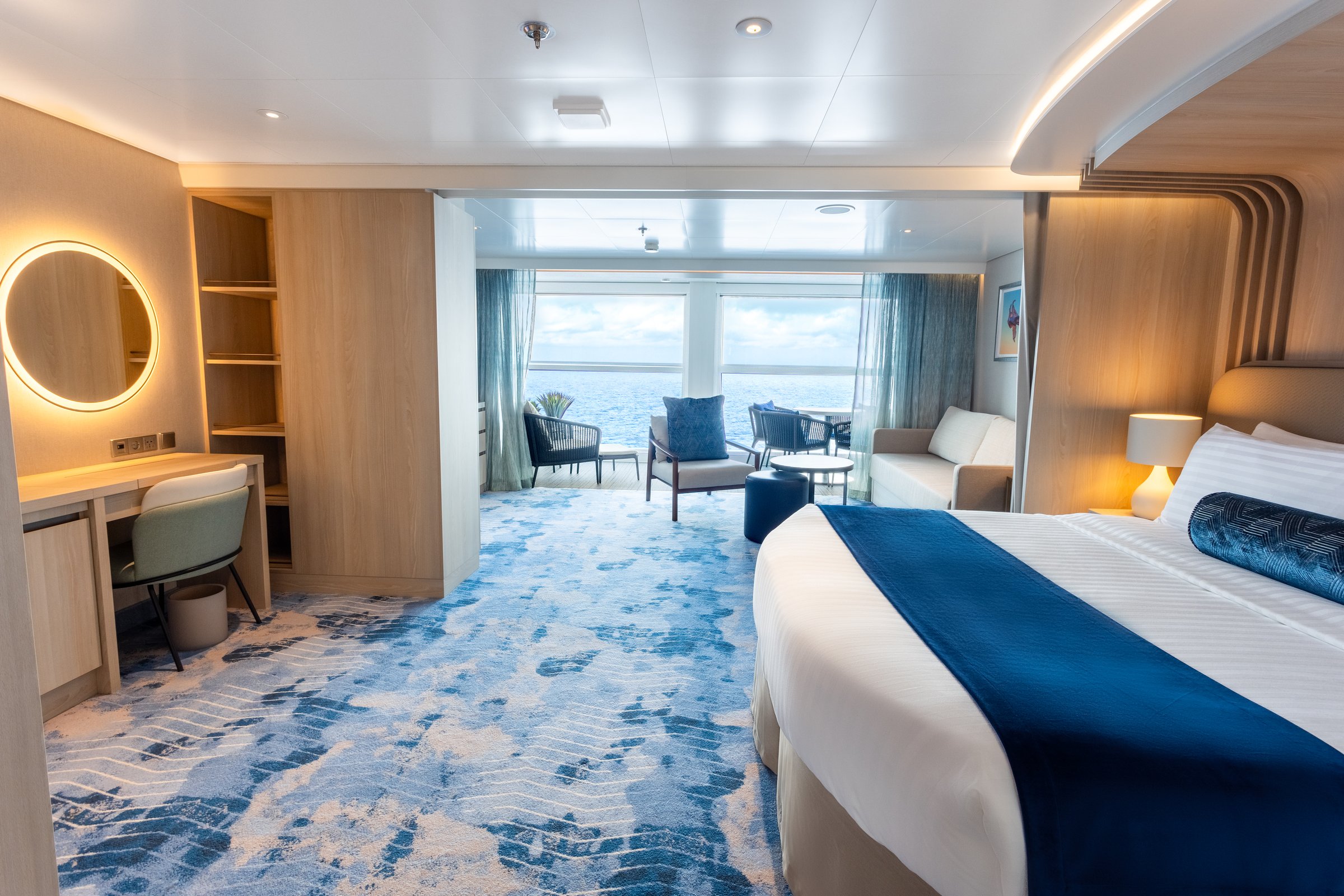 Icon of the Seas Infinite Grand Suite with king bed, lounge and floor-to-ceiling windows onto the sea