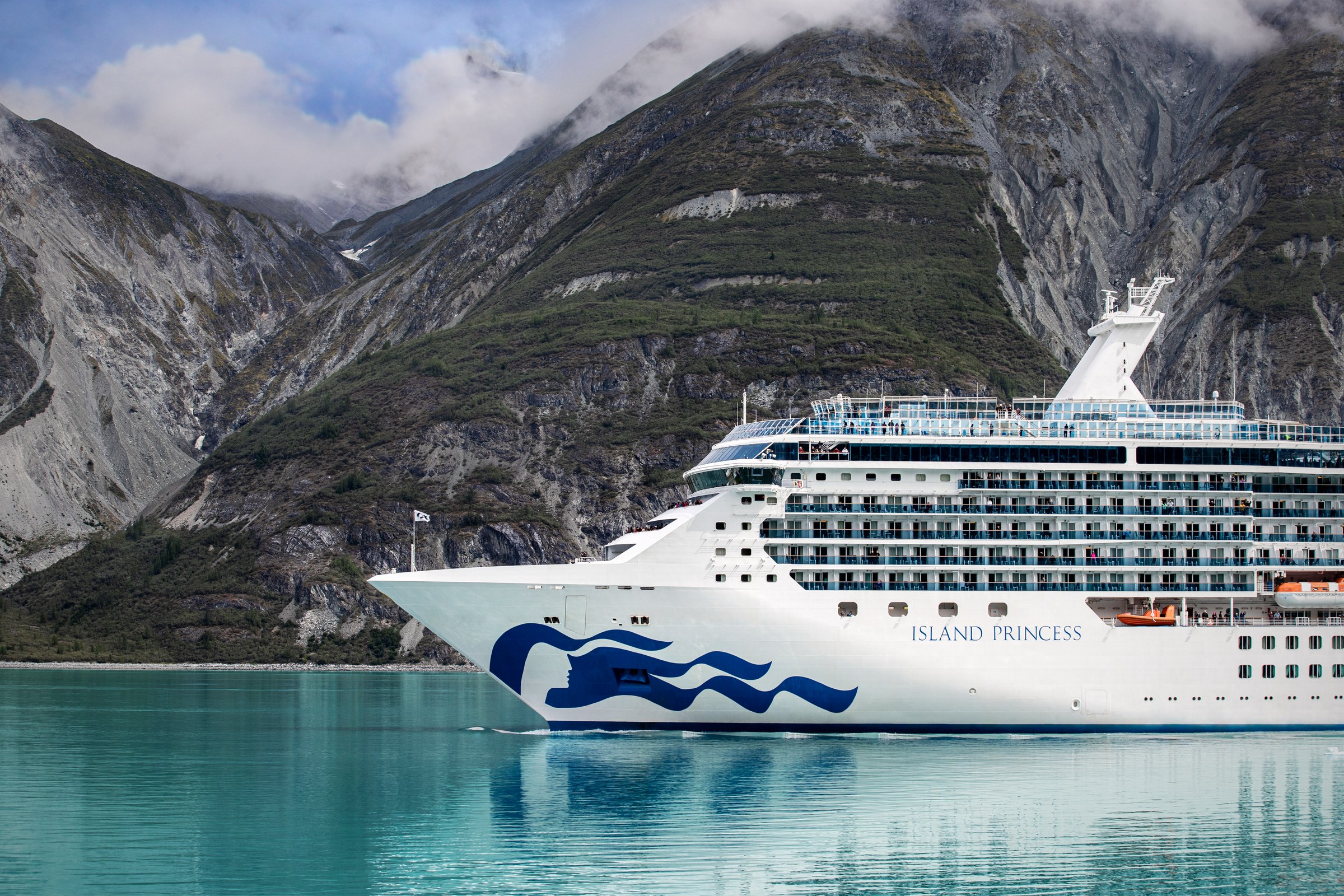 Island Princess bow in Alaska with snowy mountains behind, ship name visible