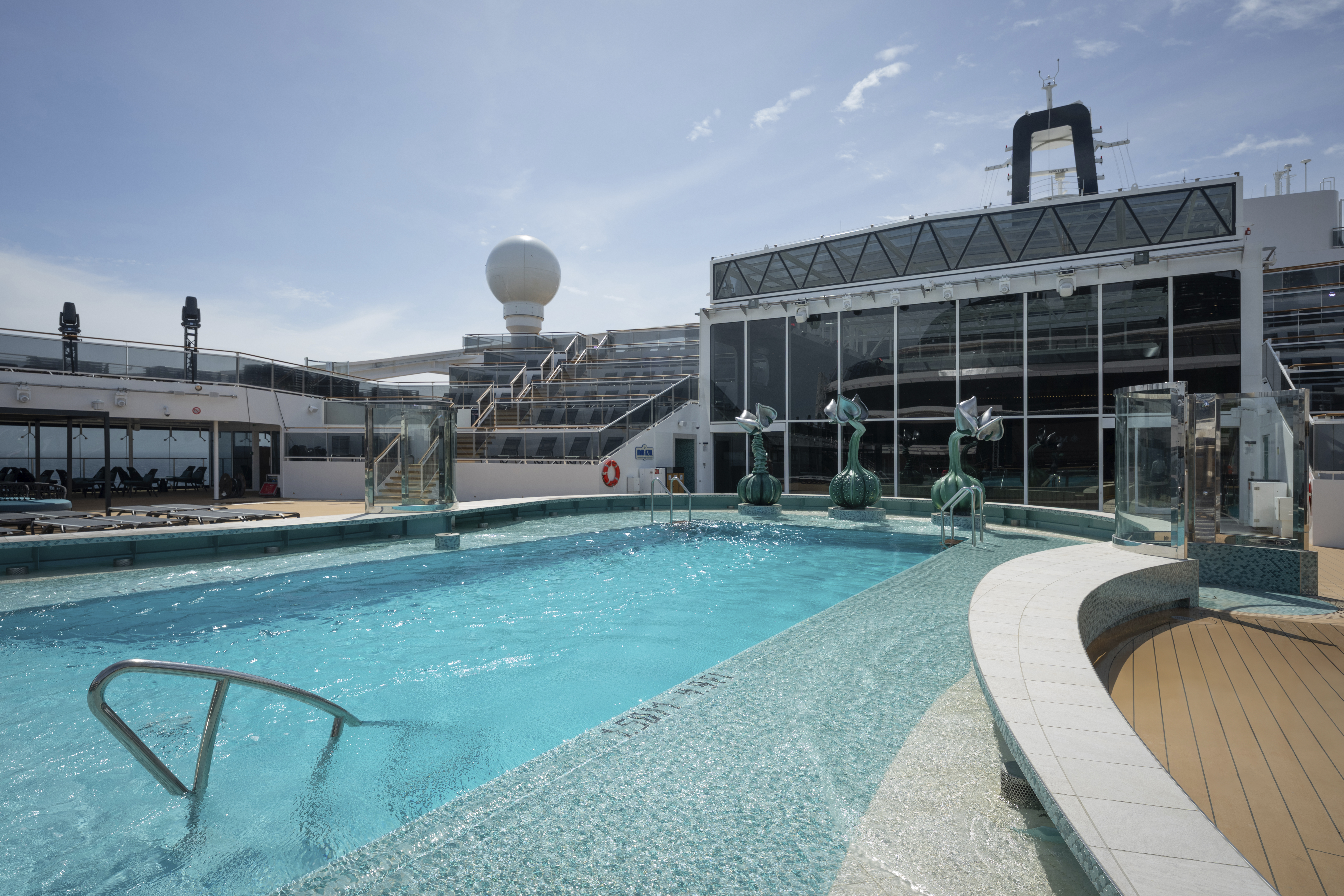 MSC World America outdoor pool with teal sculptures on a sunny deck