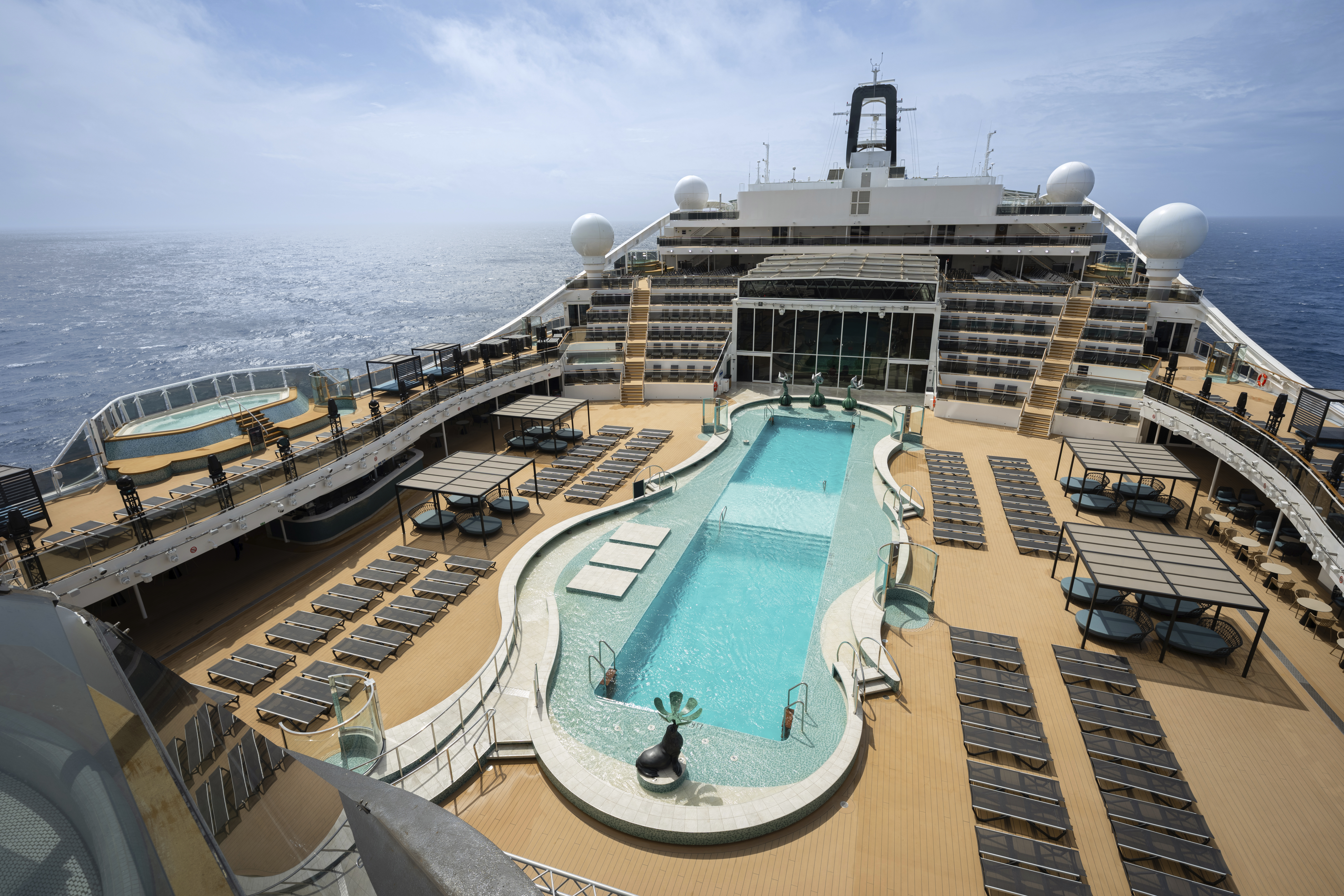 MSC World America aft pool deck with loungers and cabanas under blue sky