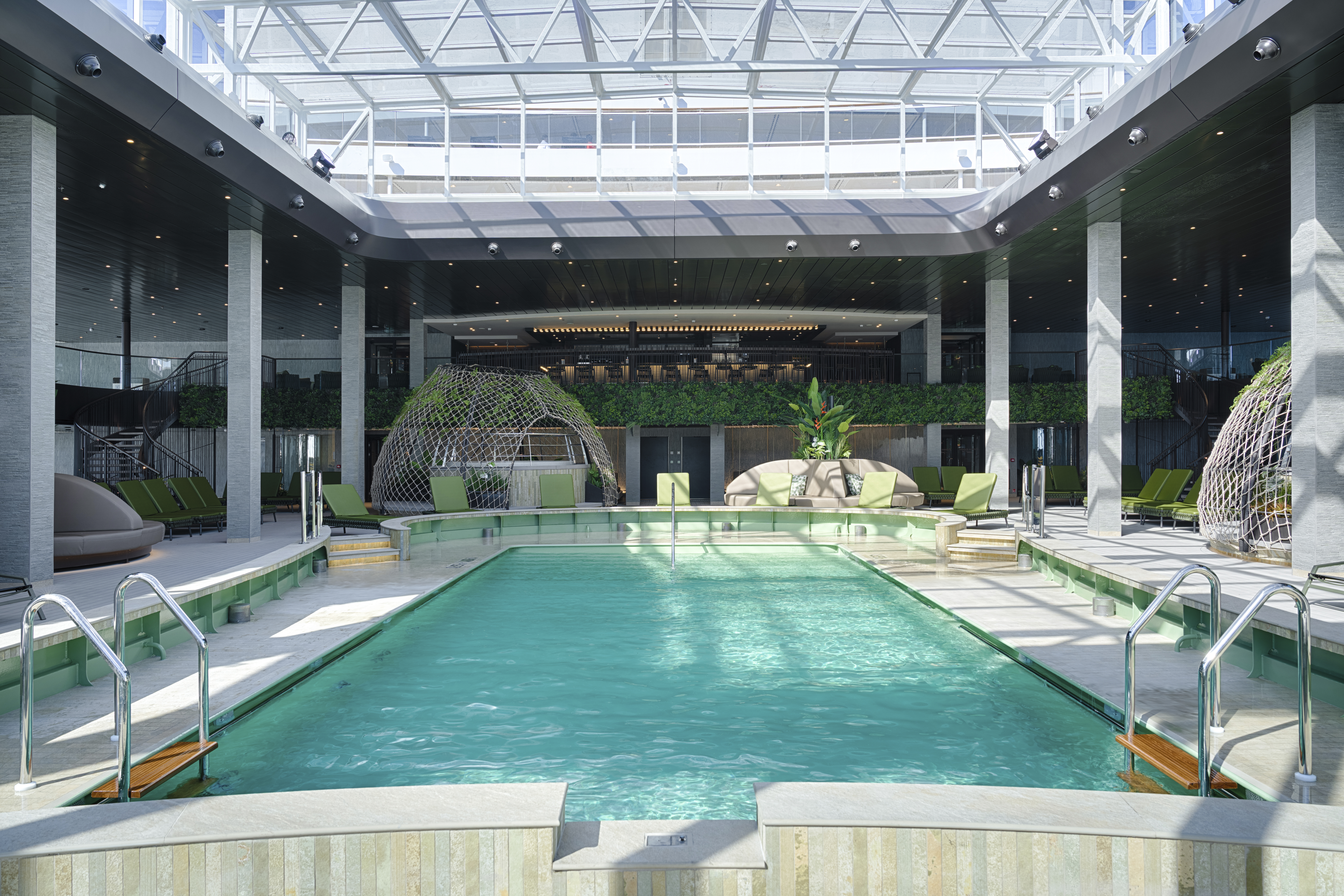 MSC World America glass-roof indoor pool with lime loungers and dome cabanas