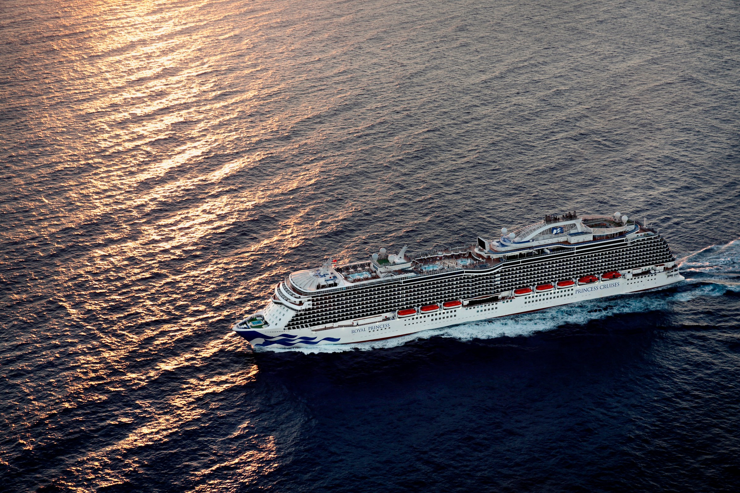 Royal Princess aerial at golden hour, ship name visible on the bow