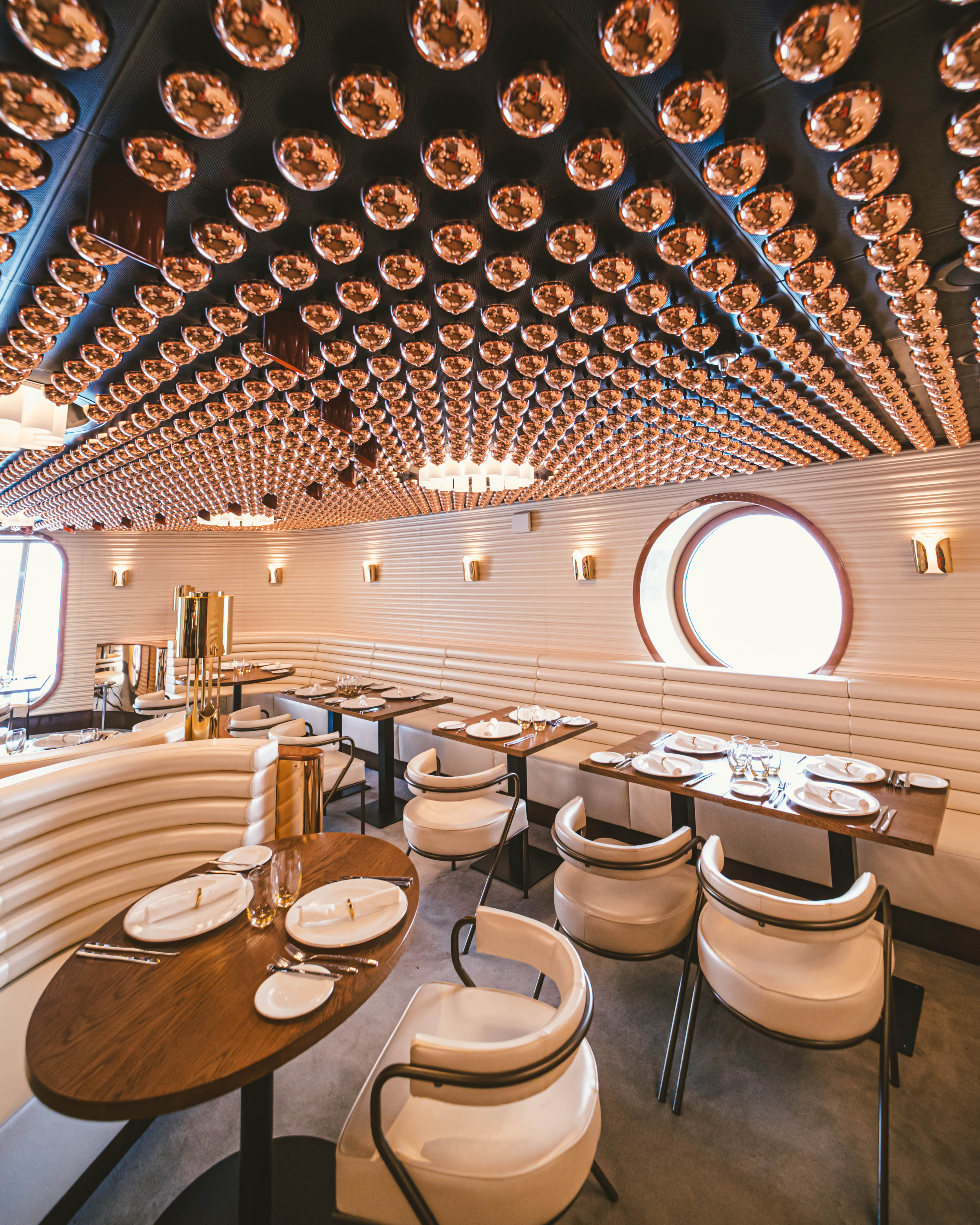 Bright Wake dining room with sculptural ceiling lights and set tables.
