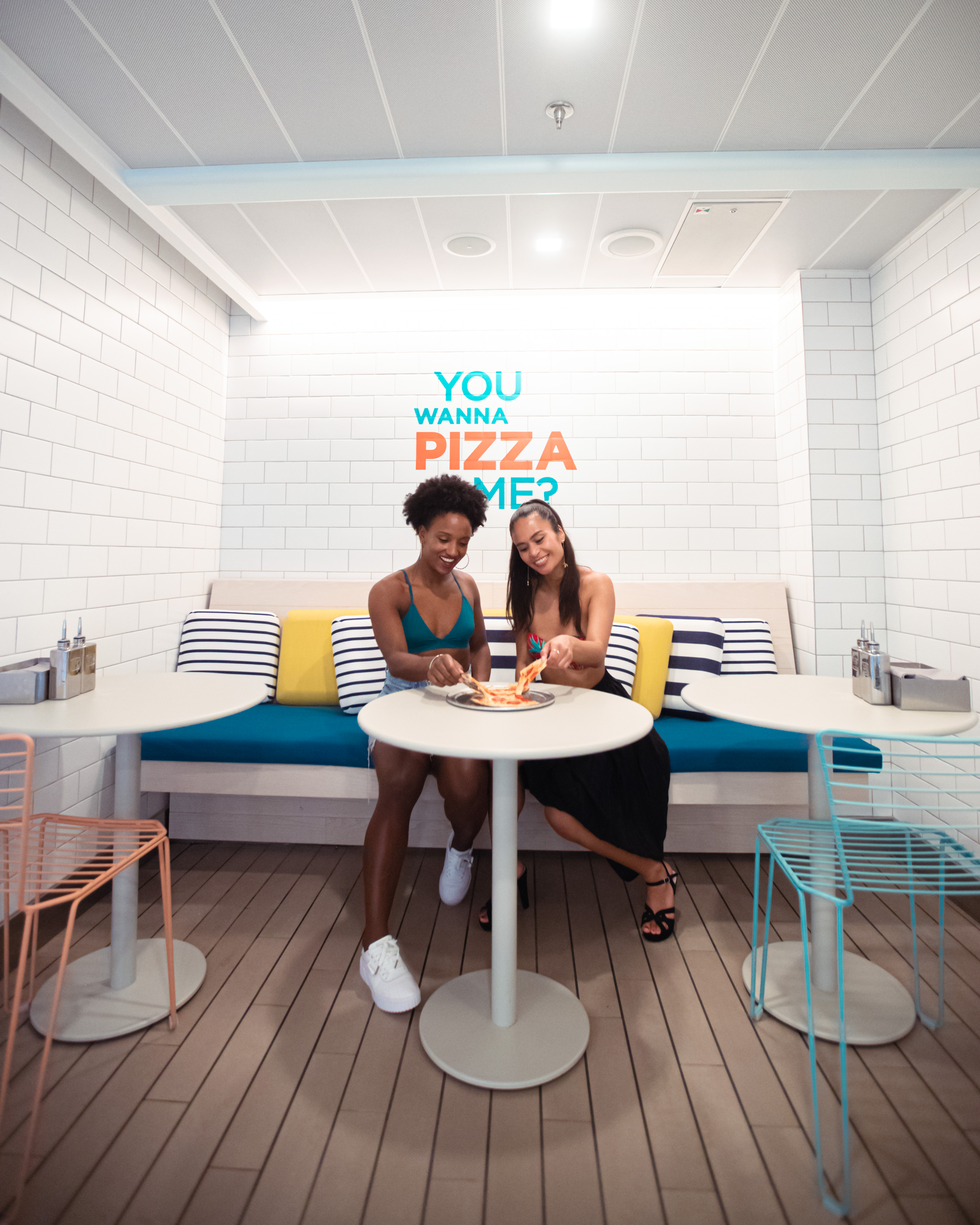 Two women enjoying pizza in the bright Pizza Place.