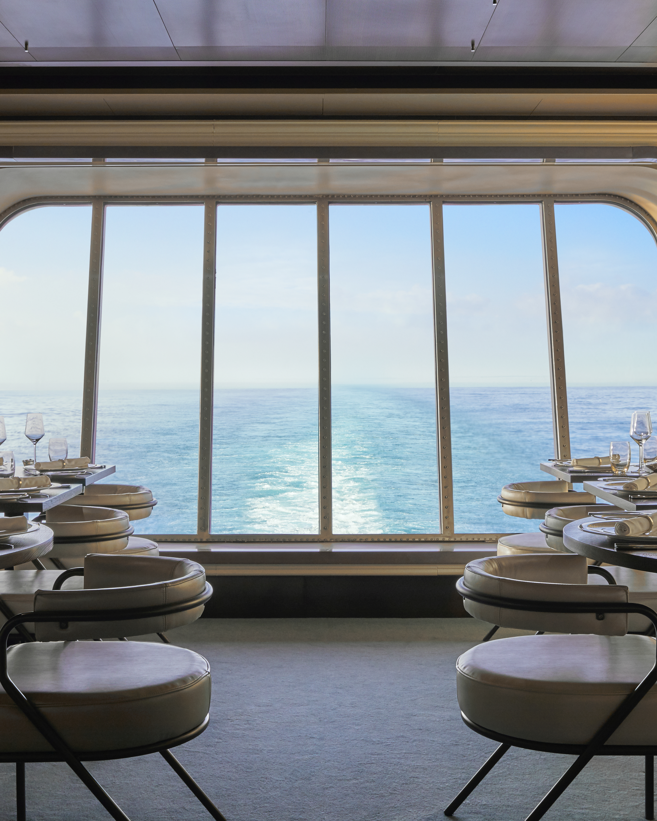 The Wake dining room with sunny ocean view through aft windows.