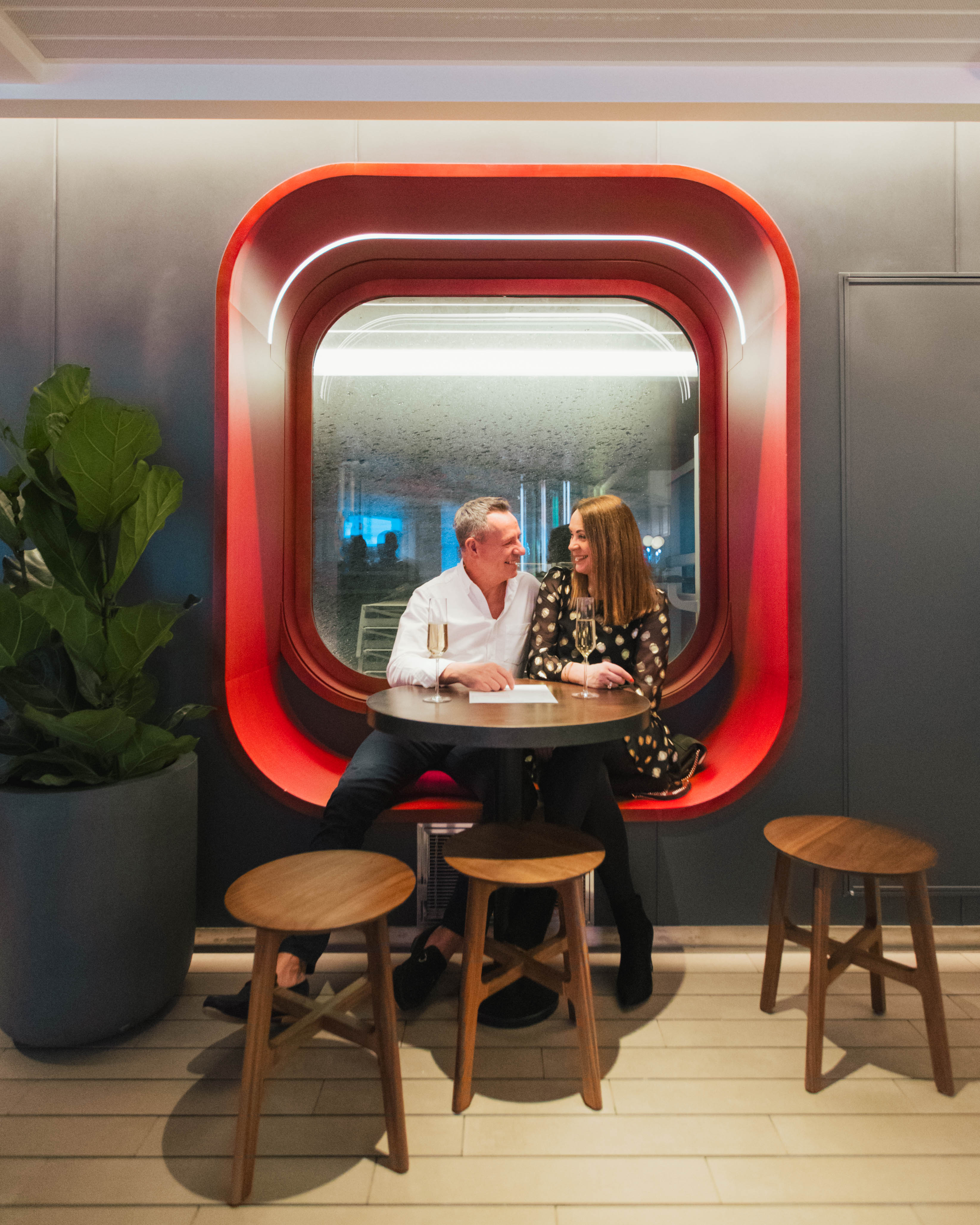 Couple enjoying champagne in a bright red window nook.