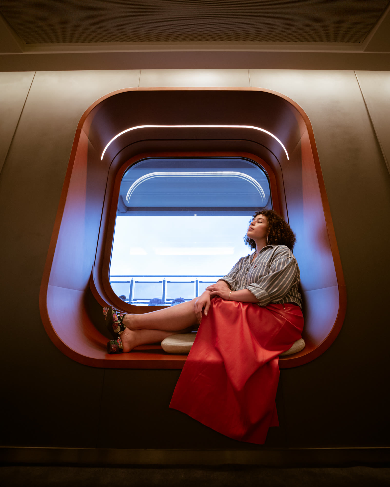 Woman sitting in a bright window porthole.