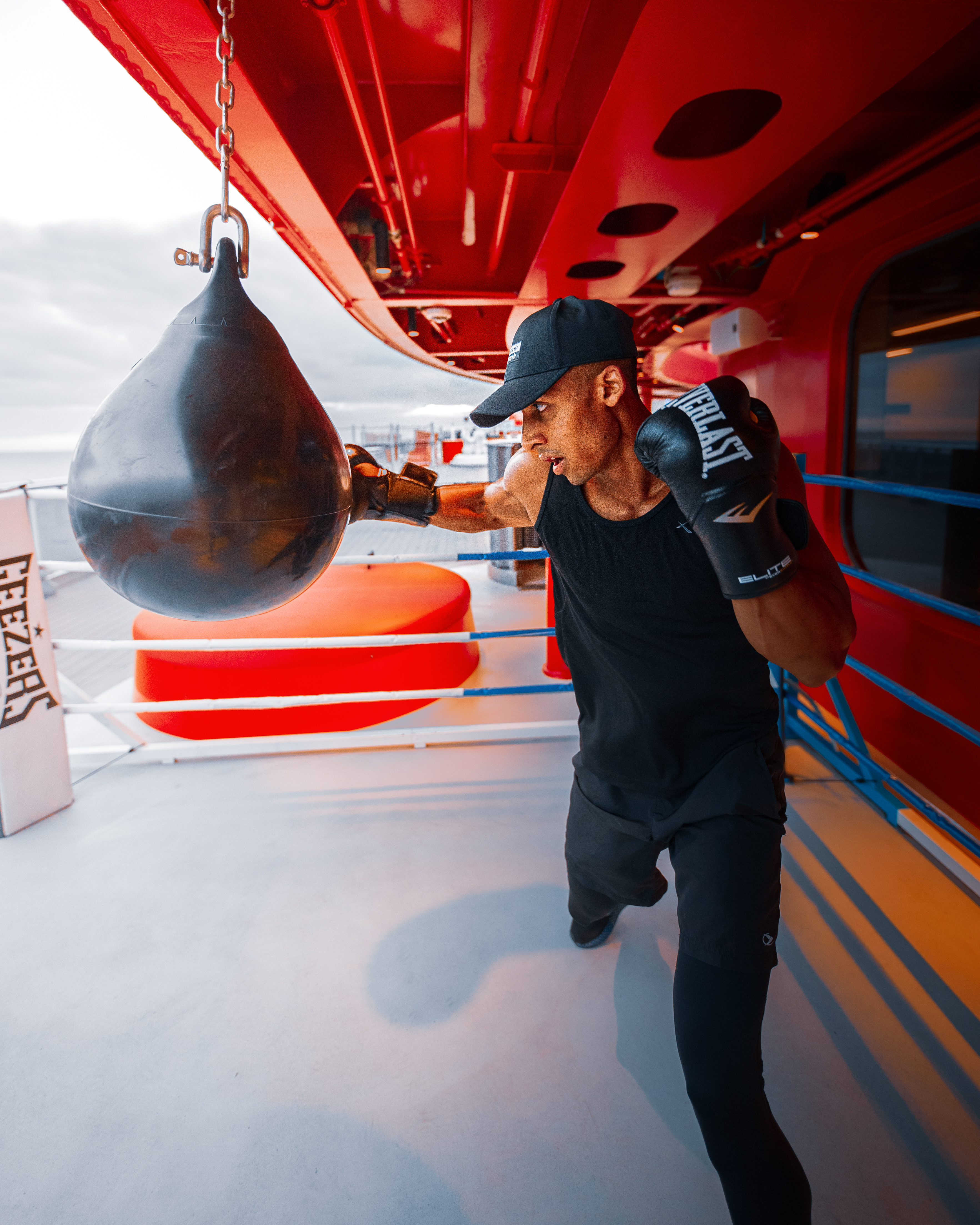 Boxer hitting a heavy bag at Training Camp on sunny deck.
