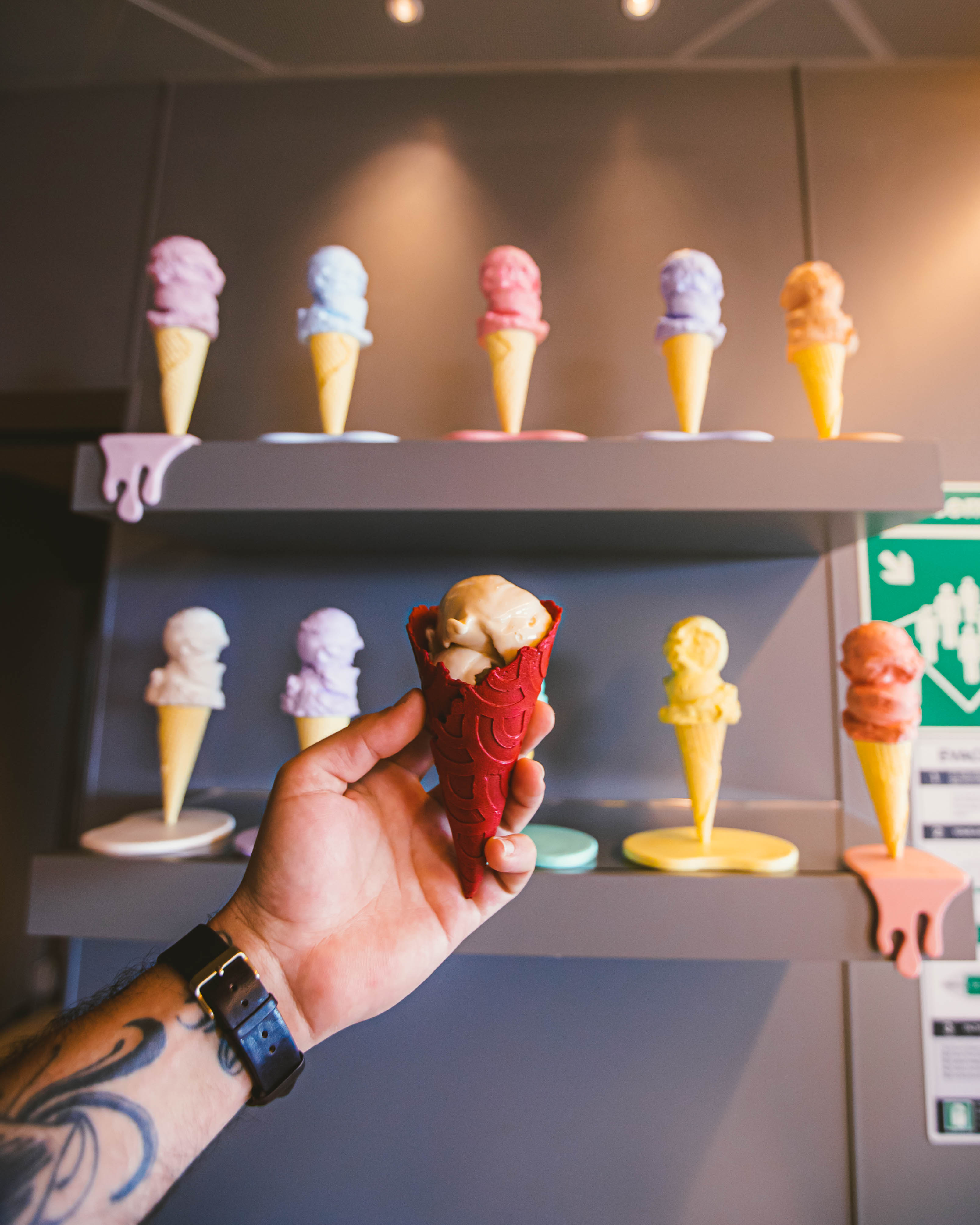 Hand holding a red waffle cone at Lick Me Till Ice Cream.