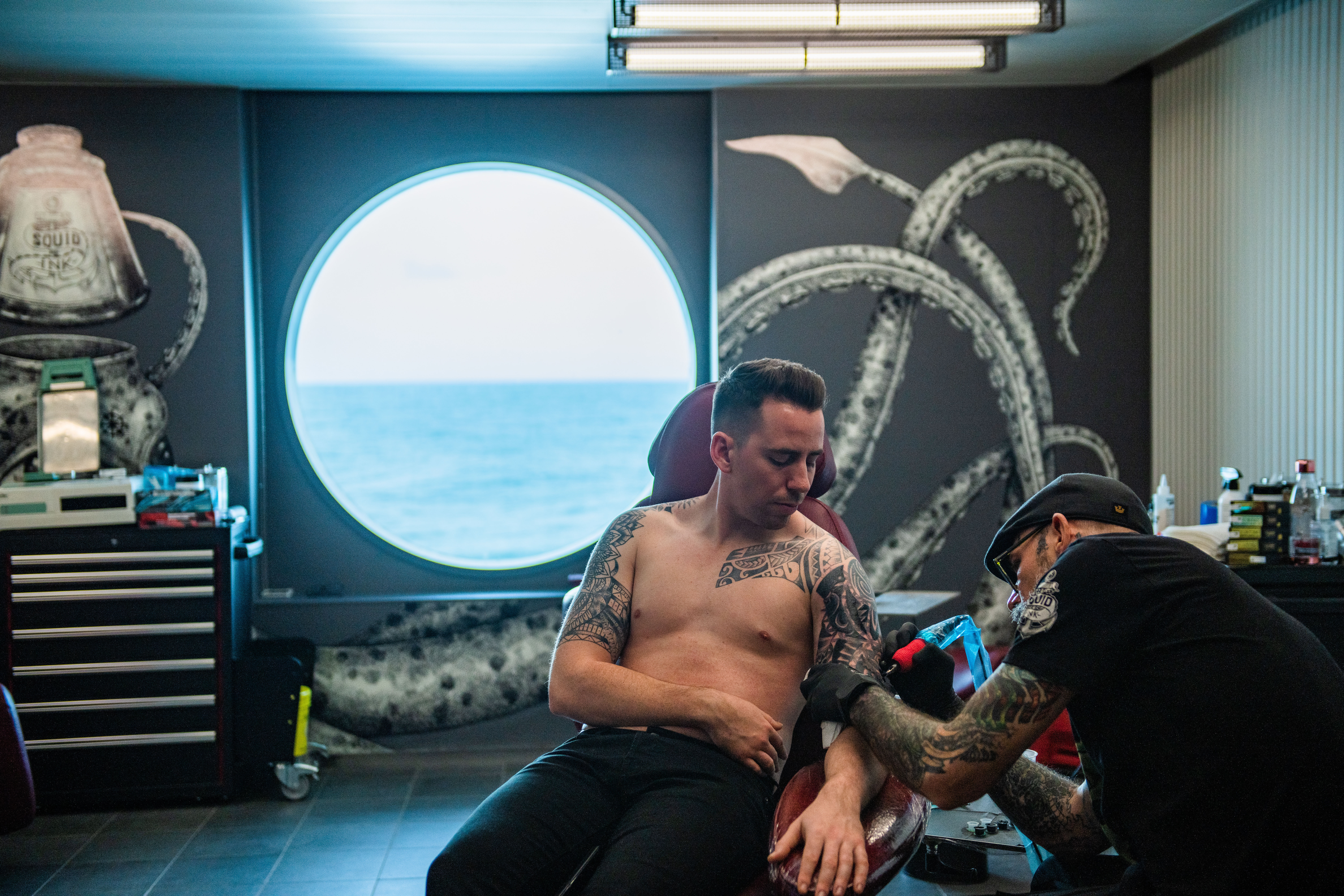 Squid Ink tattoo parlor with ocean through a round porthole.