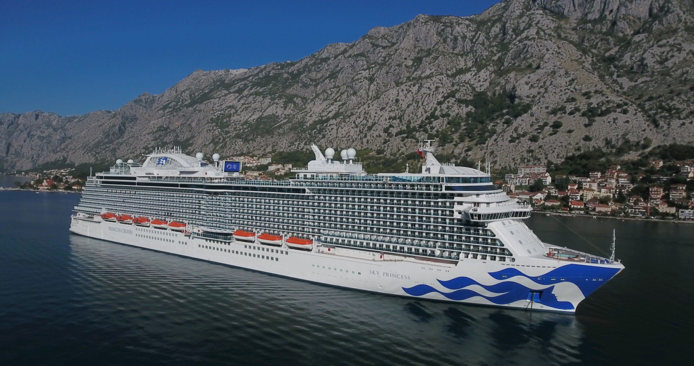 Sky Princess in the Bay of Kotor, Montenegro, below sunlit mountains